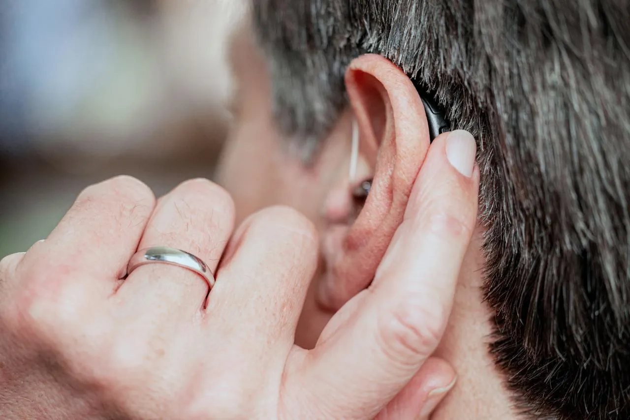 WIDEX hearing aids AI RIC Button CloseUpWithFingerPress