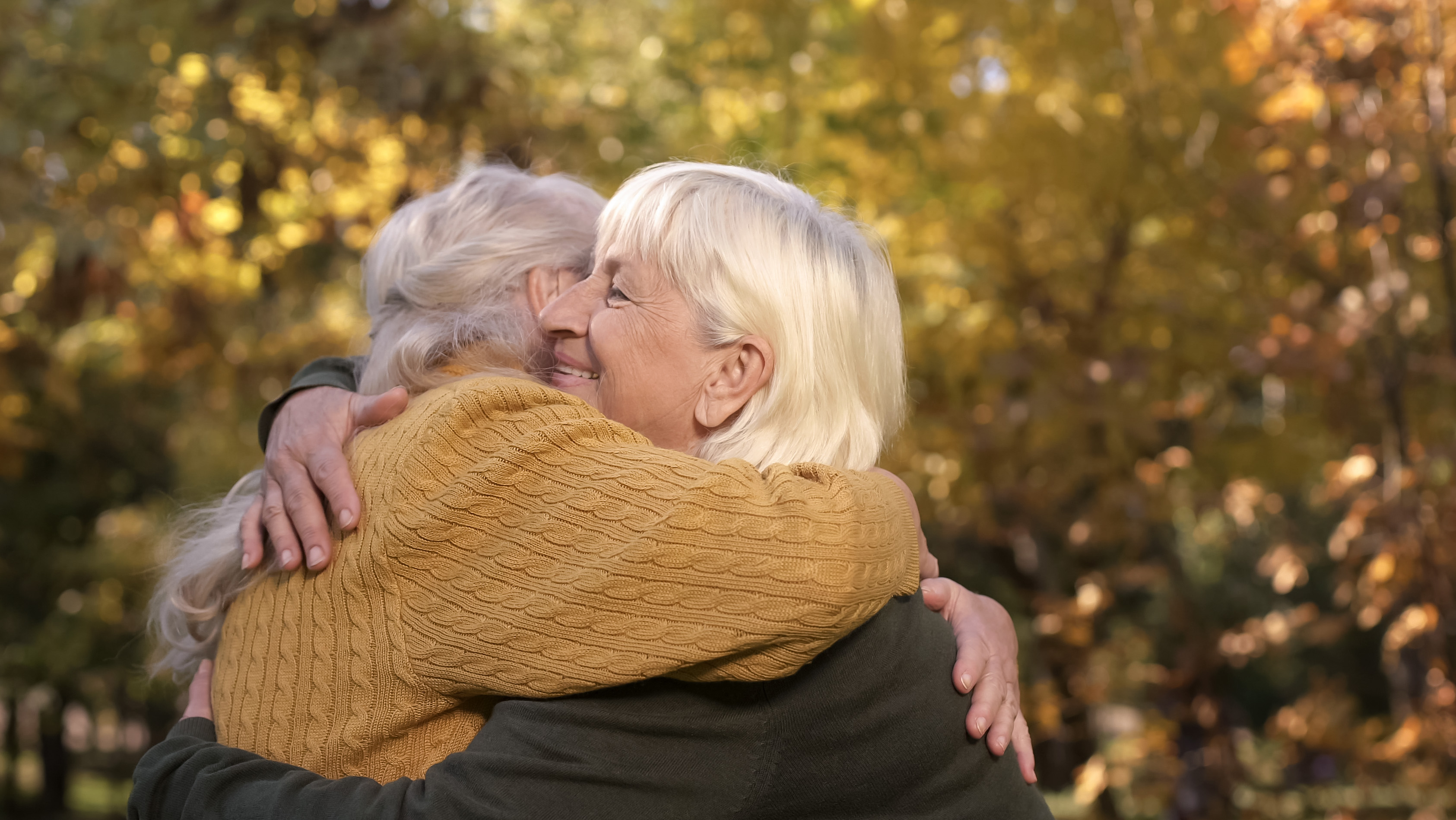 elderly friends outside hugging