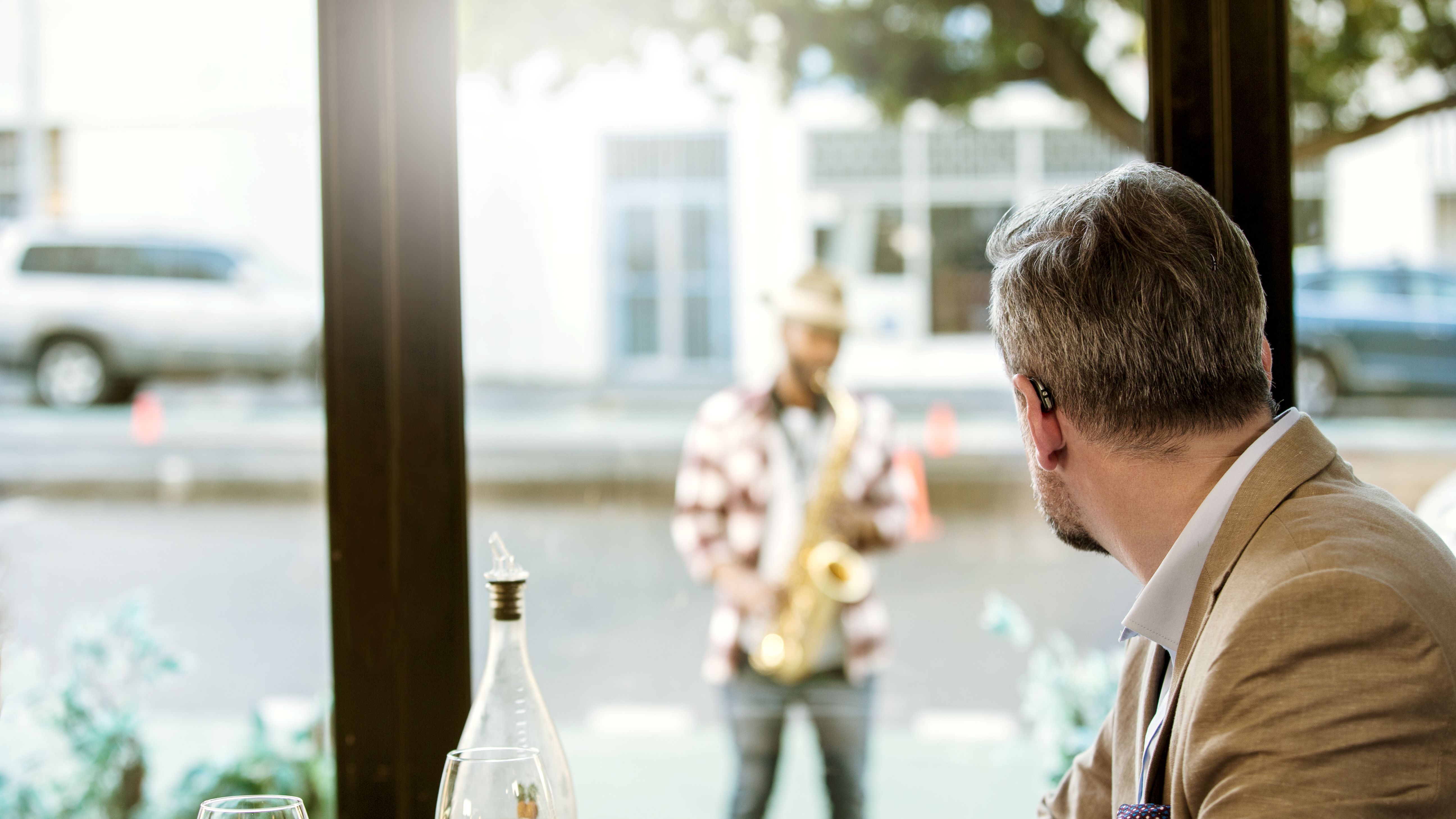 Friends at a café, where someone is straining to hear over the background noise due to hearing loss