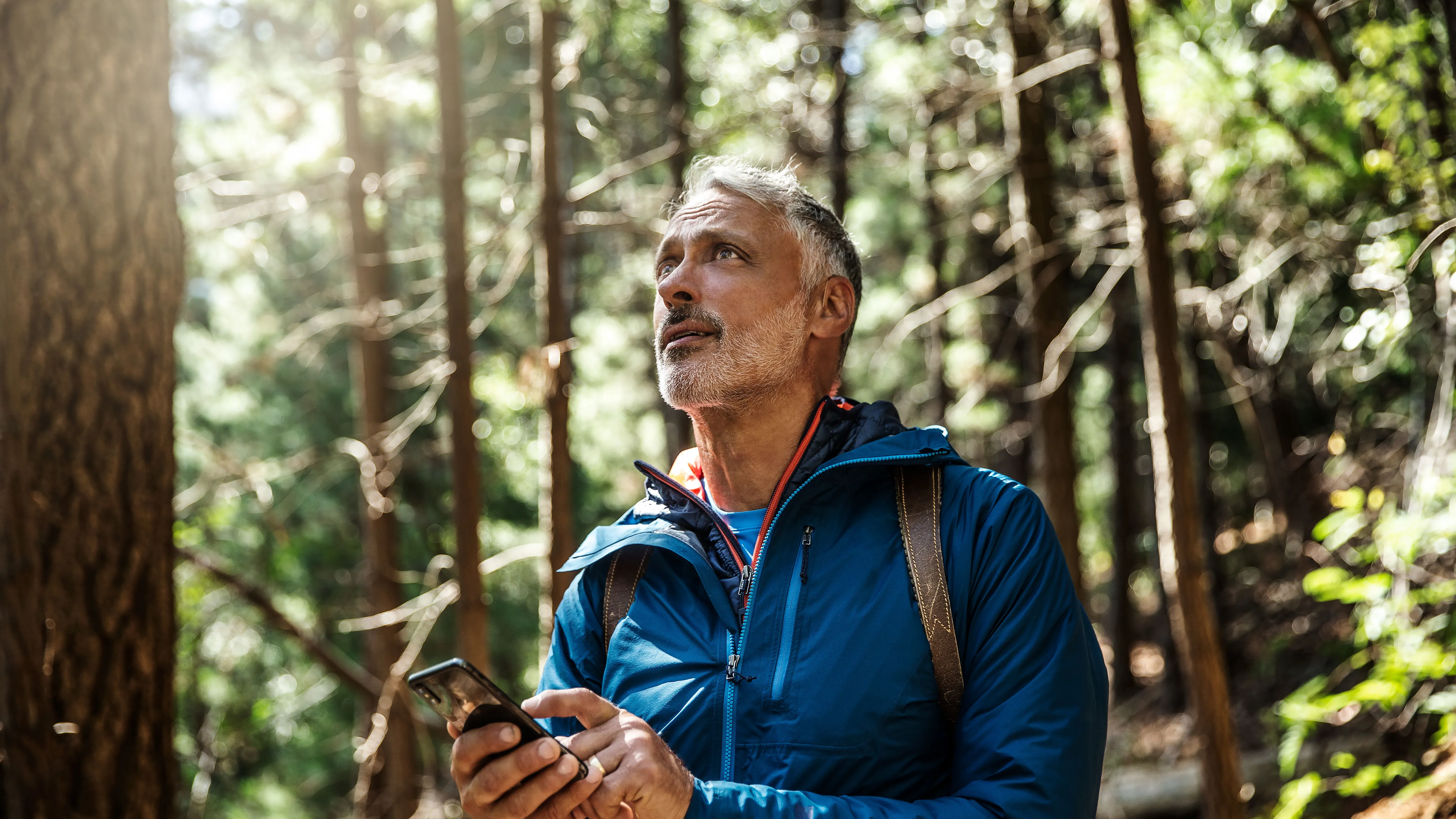 man in forest with hearing loss using a phone