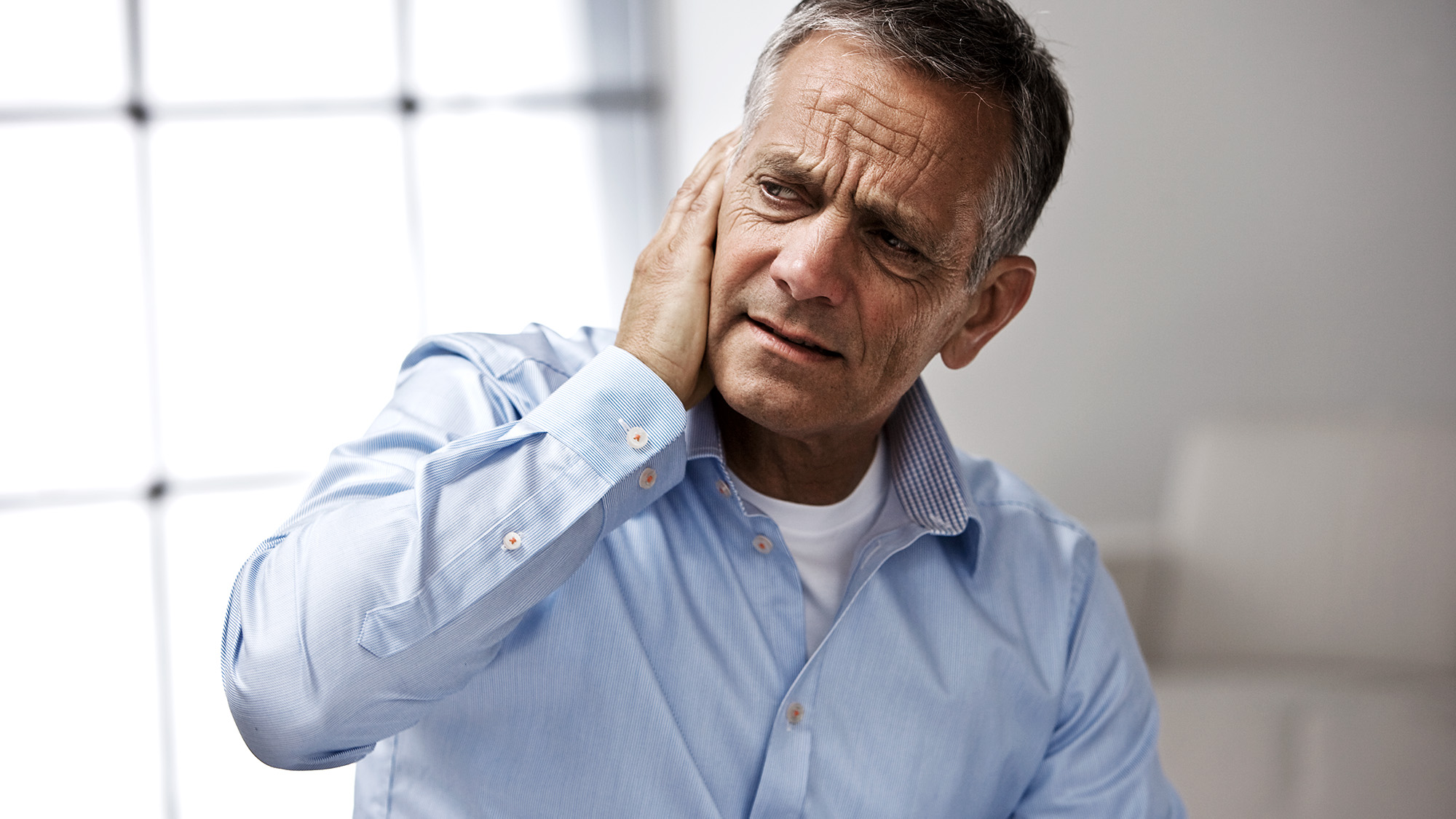 A man sitting alone, appearing isolated due to hearing loss, representing the emotional impact of hearing difficulties.