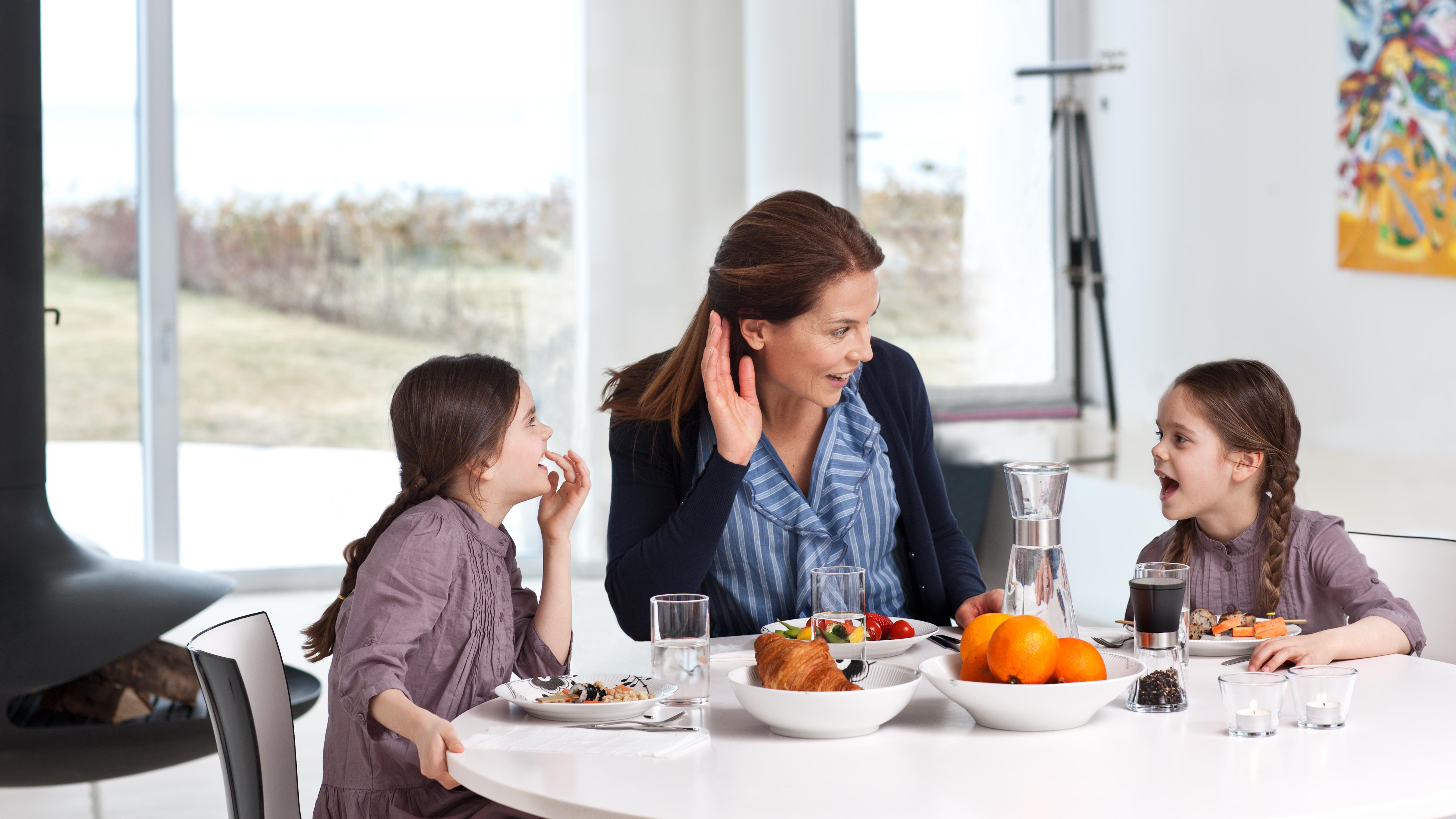 Mother with hearing loss wearing hearing aids talks with her children.