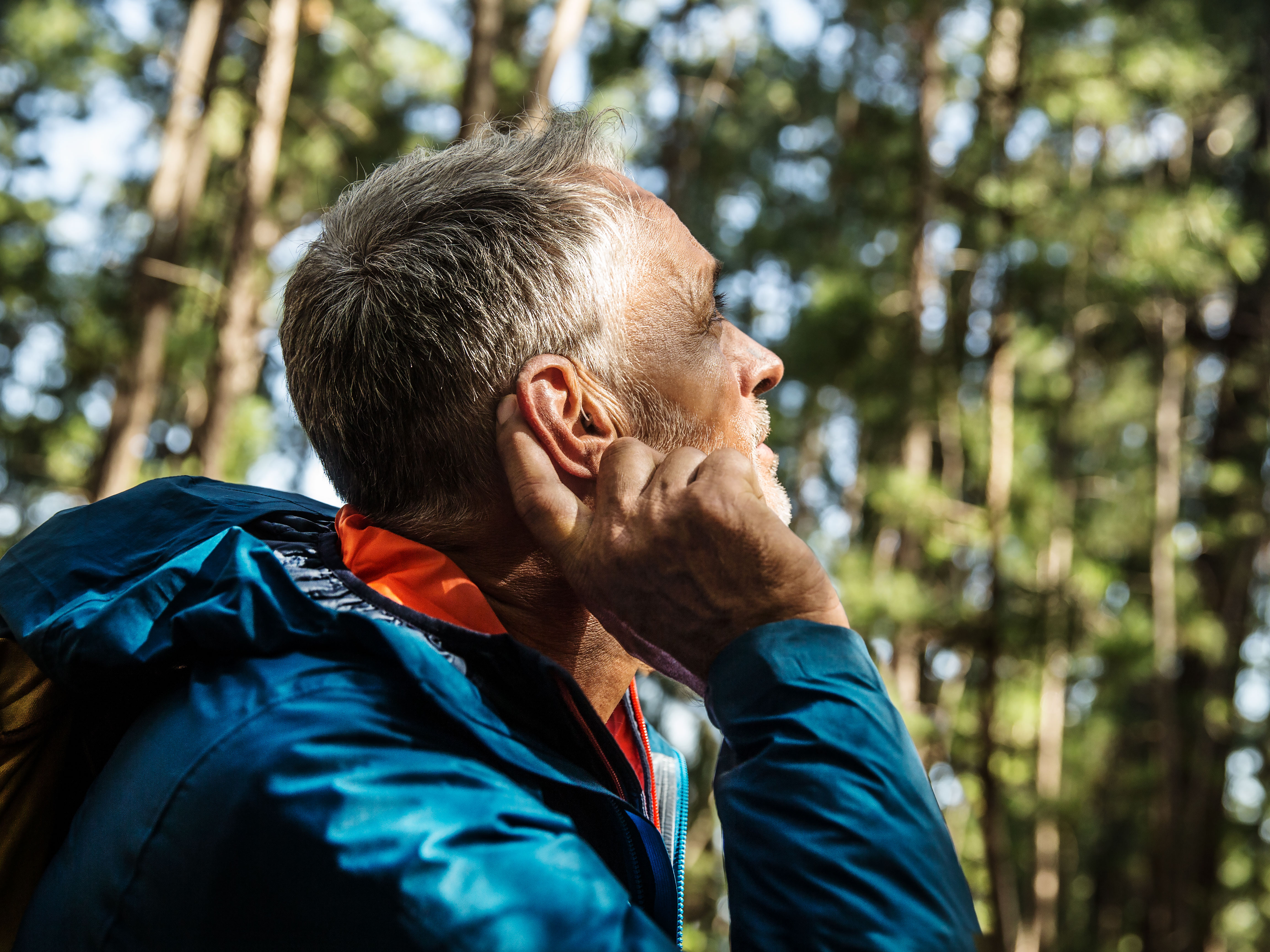 man in forest listening with hearing aids