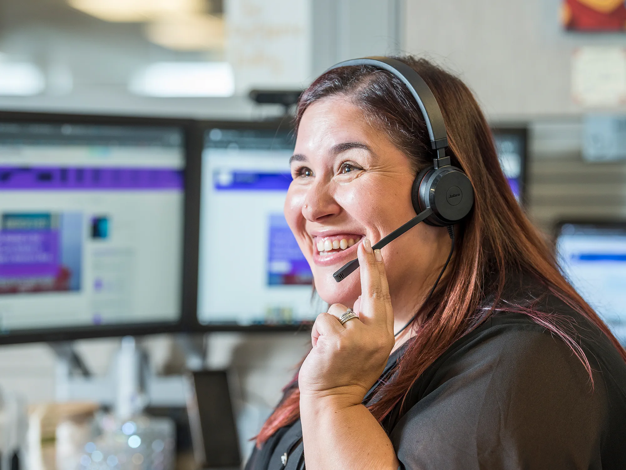 Woman talking into headphones working in customer care call center at WS audiology. Is yoru next career with us.