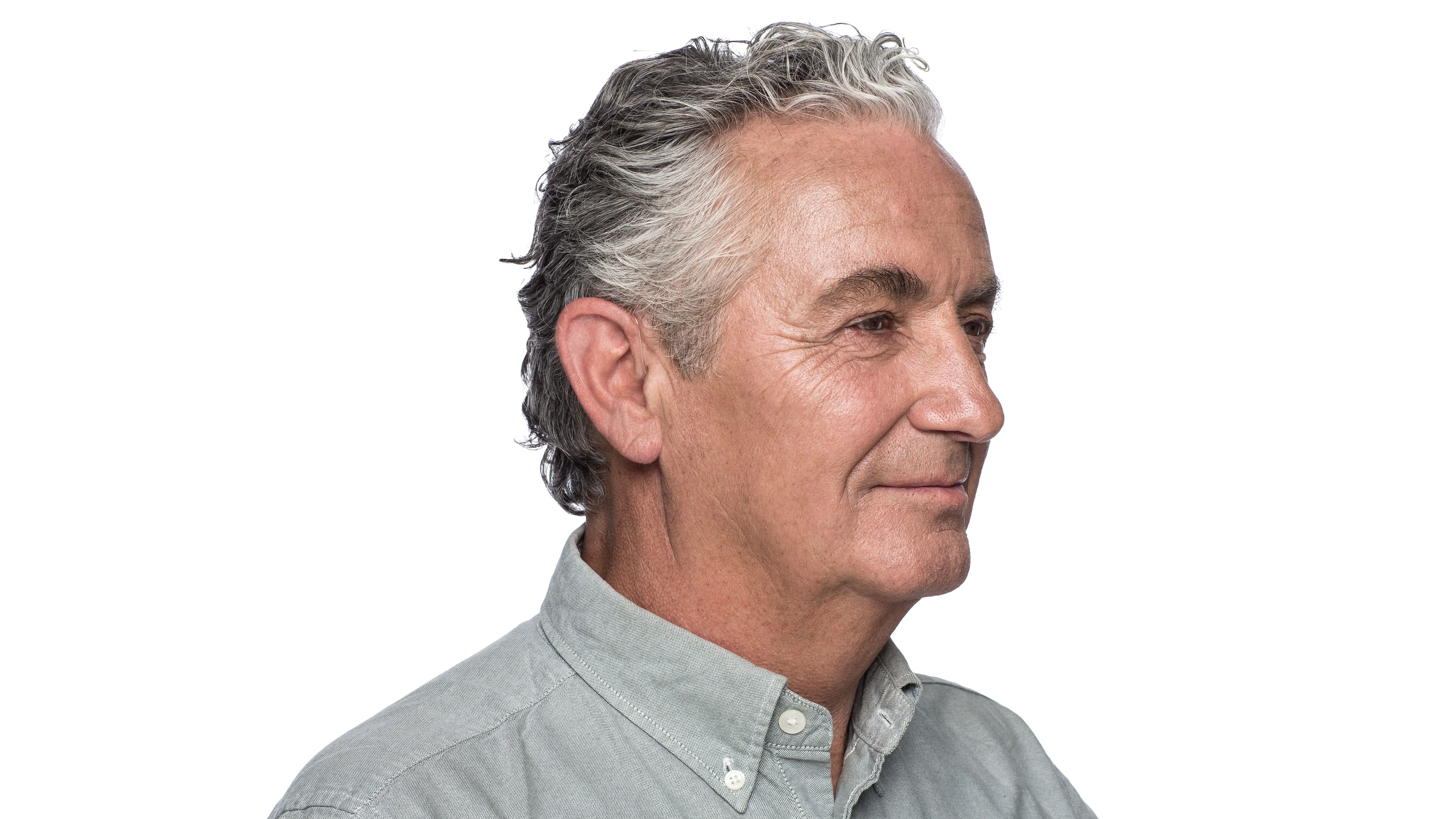 Man wearing behind the ear hearing aid seen from his right side.