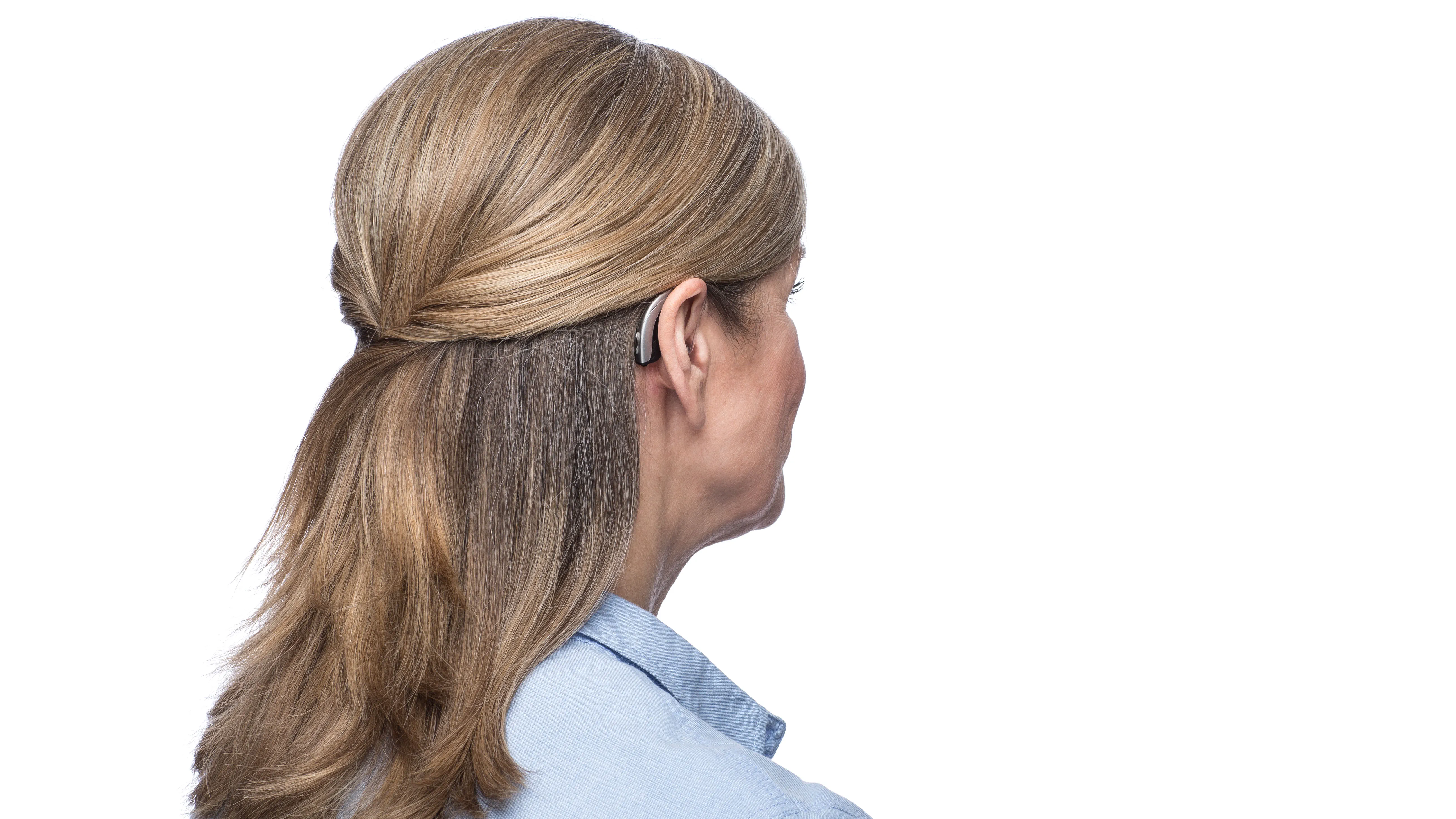Woman wearing behind the ear hearing aid seen from side.