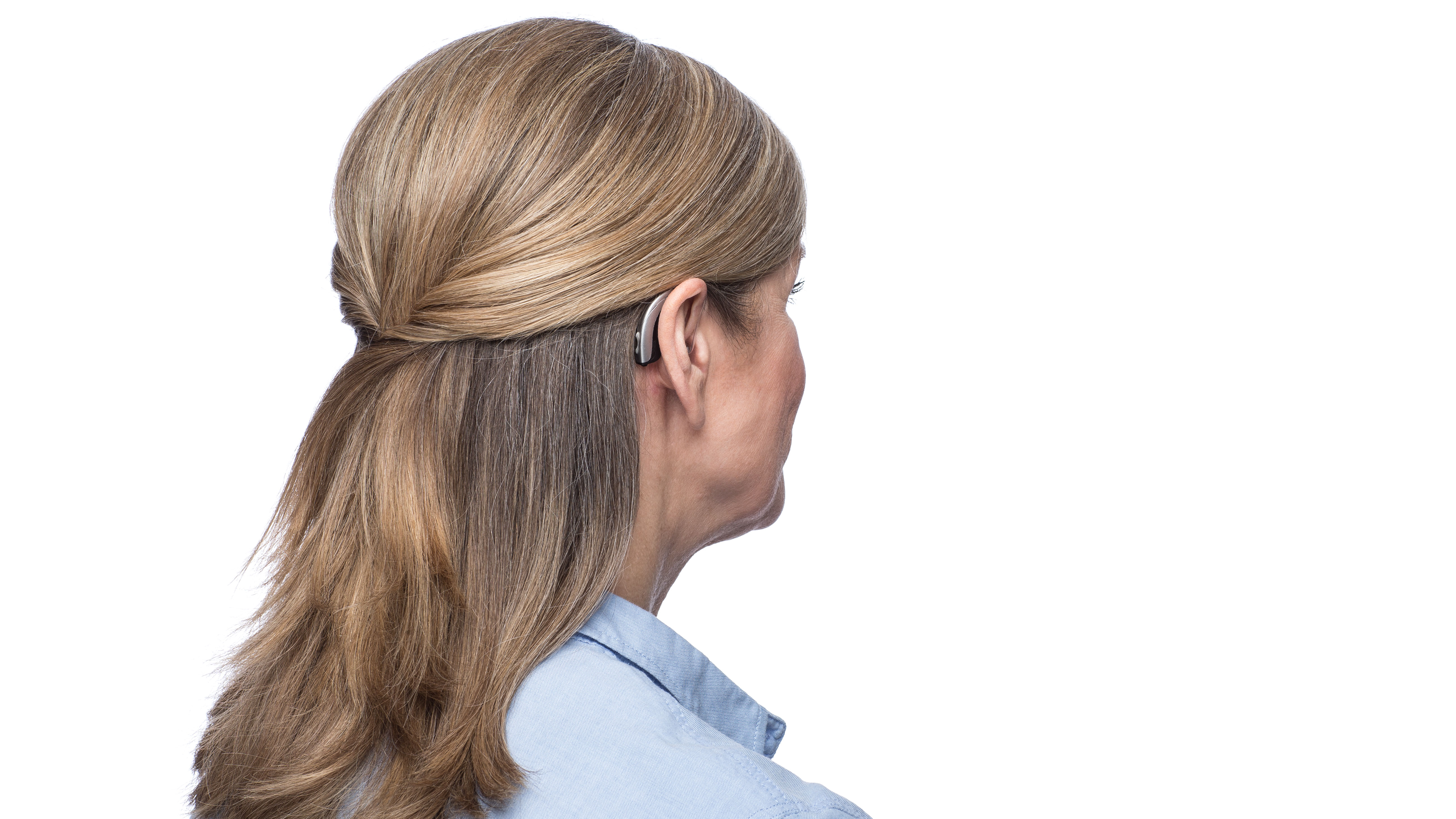 Woman wearing behind the ear hearing aid seen from side.