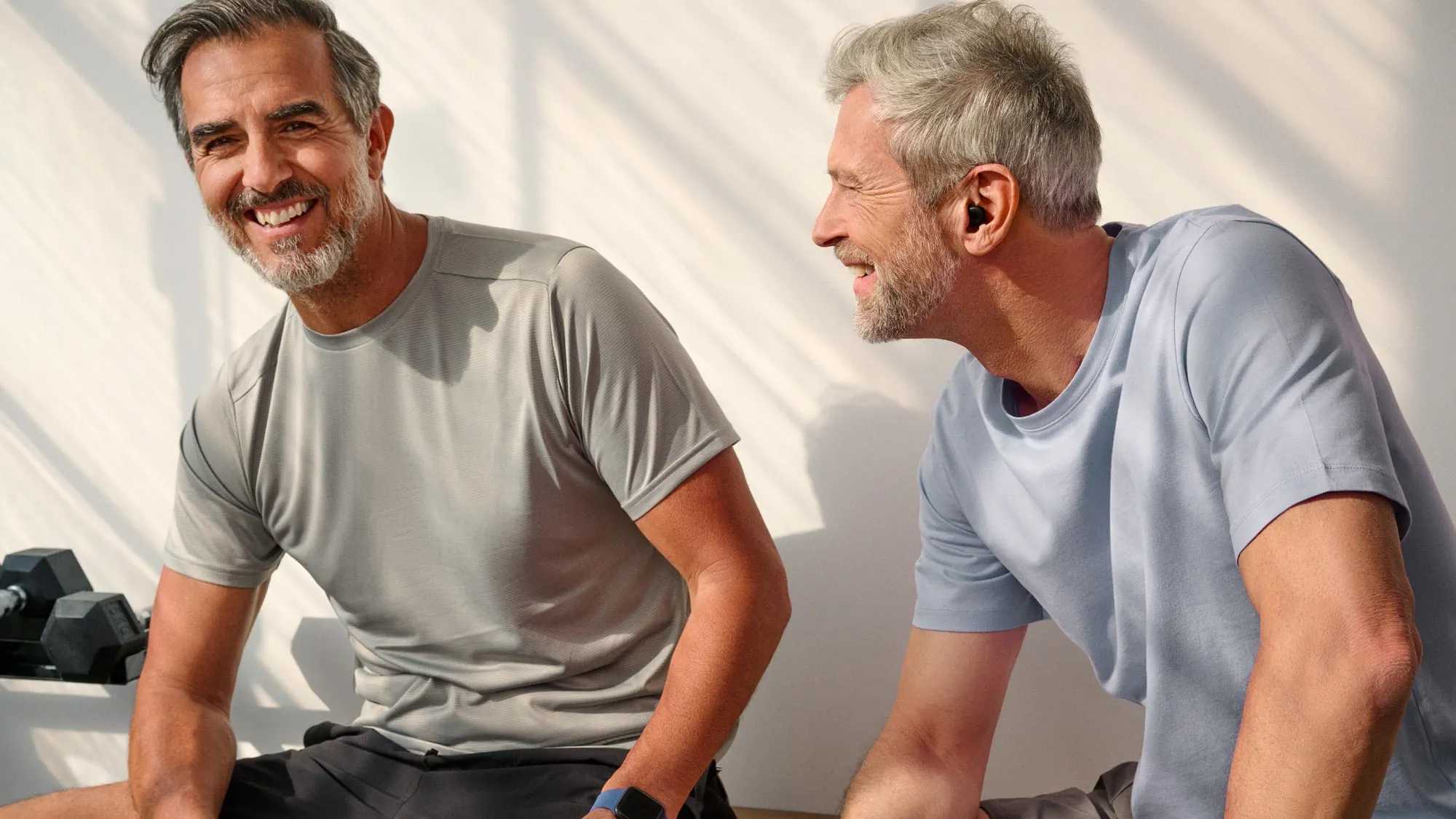 Group of men laughing at the gym, wearing hearing aids.