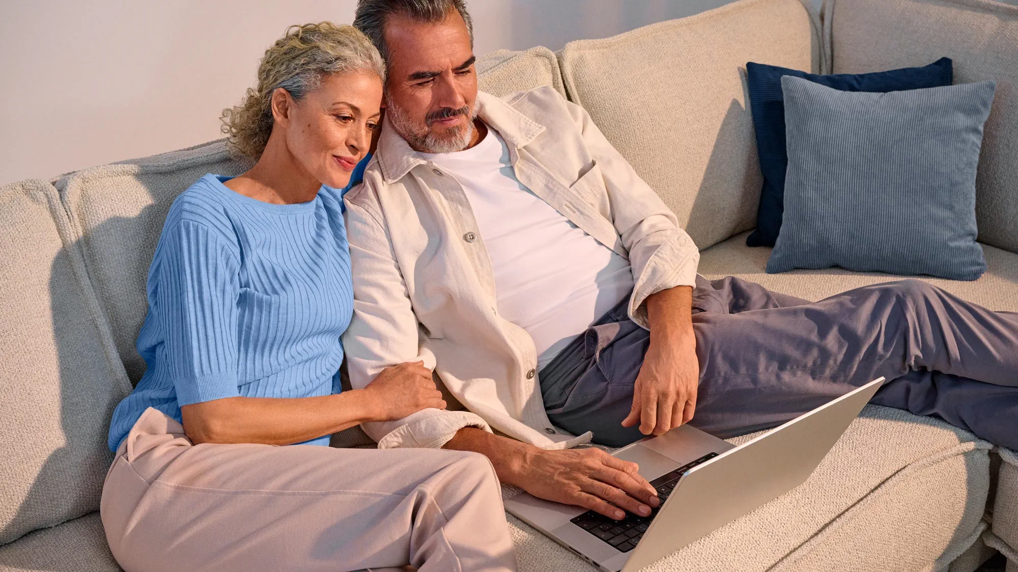 A couple looking comfortable, using technology with their hearing aids.