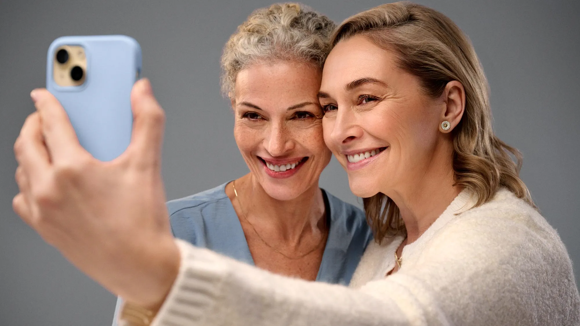Group of friends showing something on a phone, wearing hearing aids.