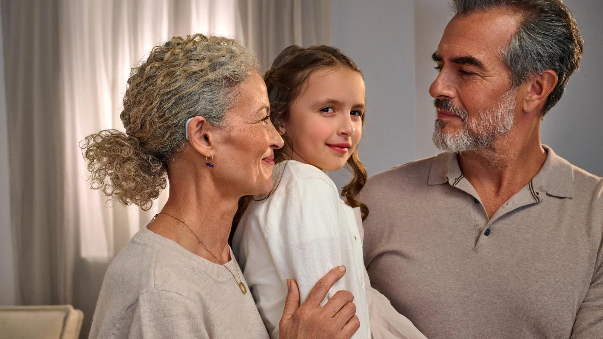 Grandparents and girl looking together, showcasing hearing aids.