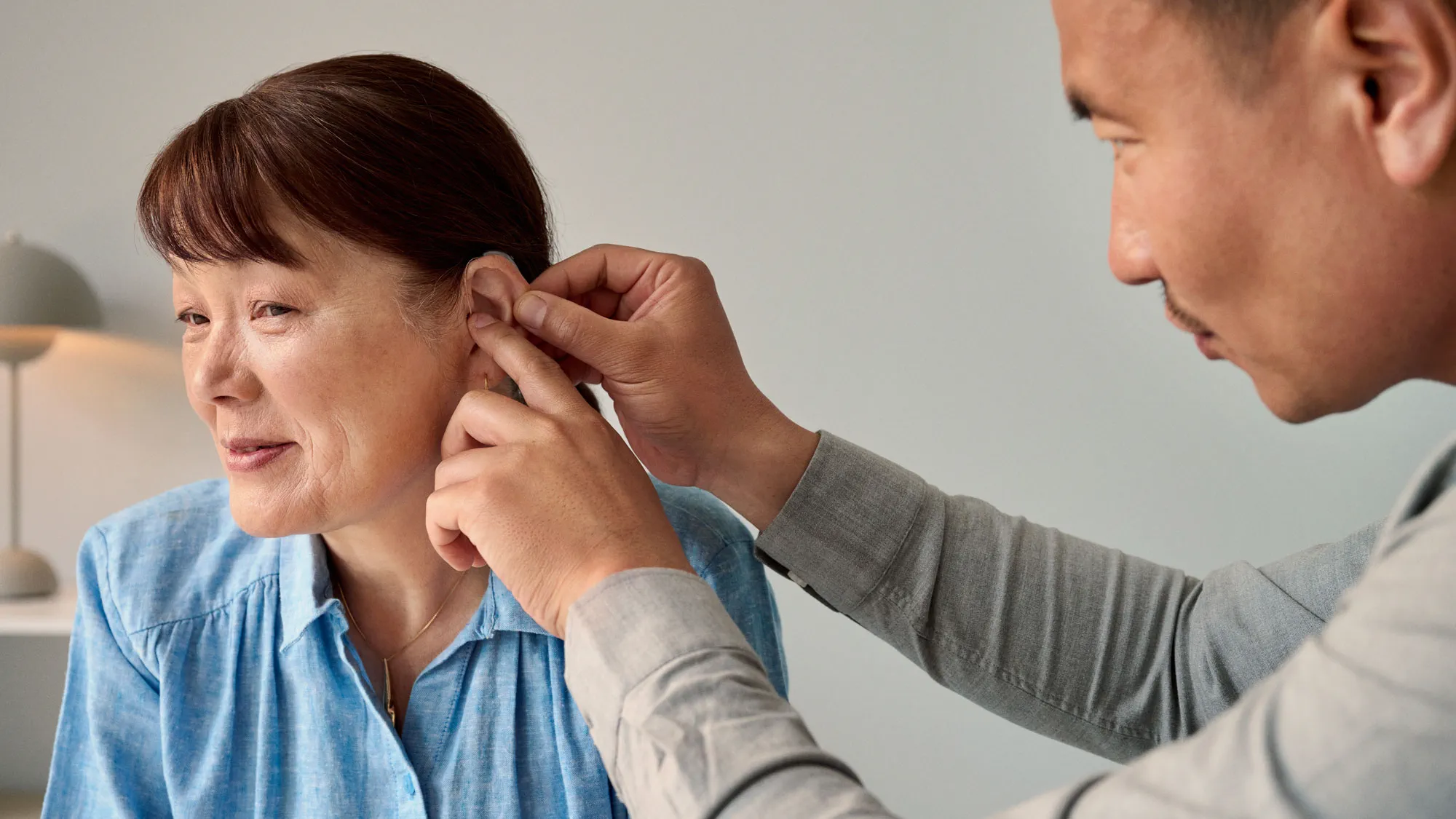 The audiologist fitting a hearing aid onto the customer during the appointment.
