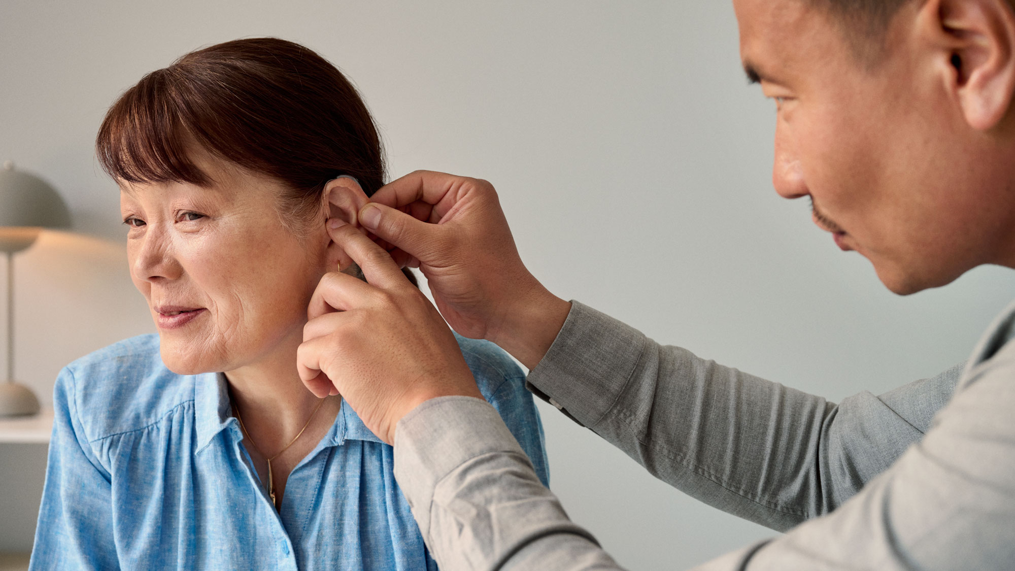 The audiologist fitting a hearing aid onto the customer during the appointment.