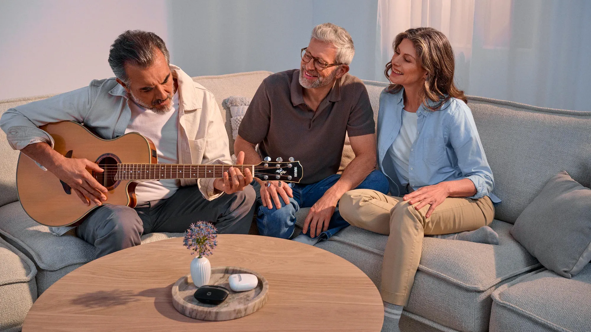 Friends captivated by a guitar performance, all wearing hearing aids.