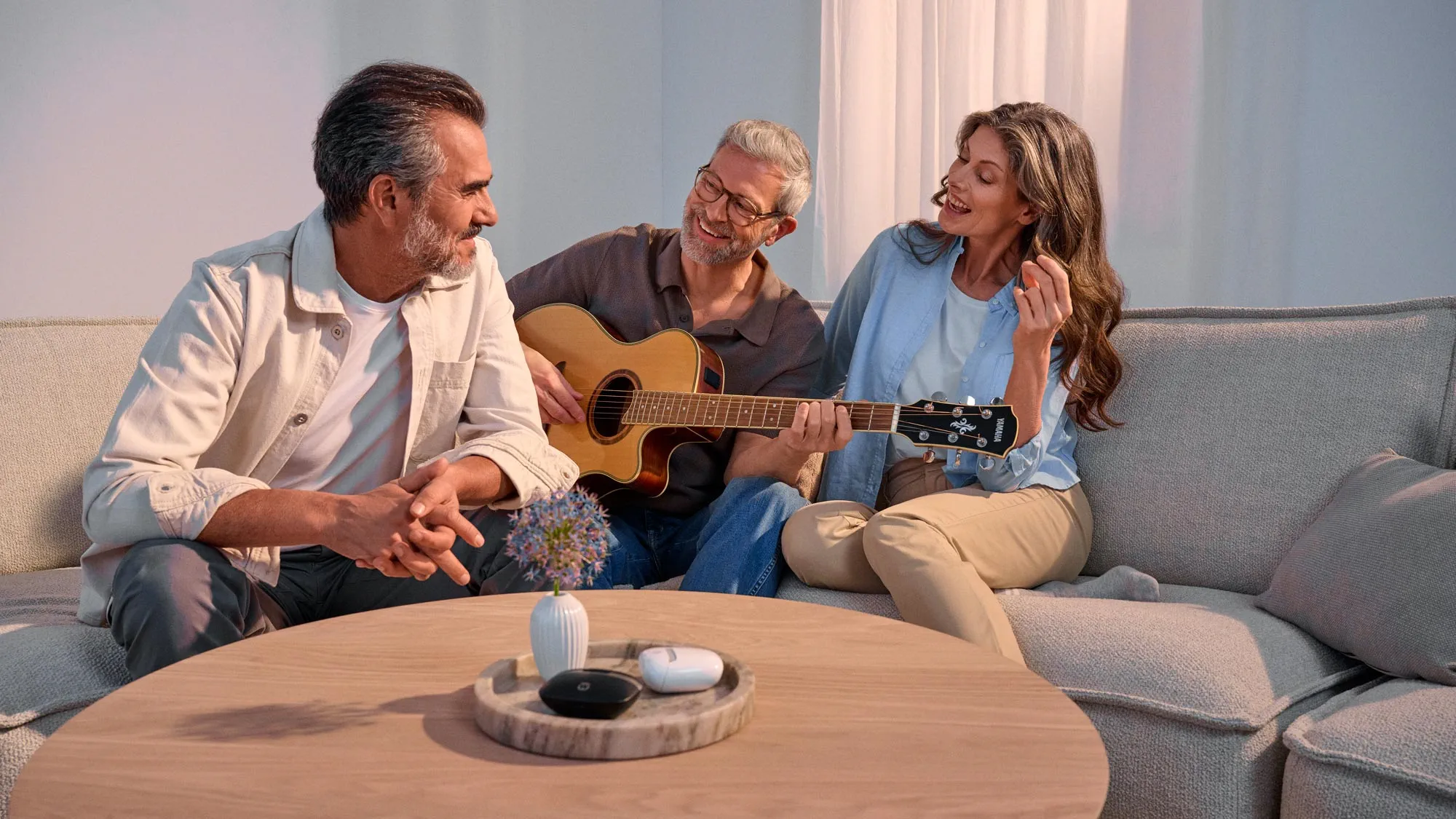 Casual gathering of friends around a guitar, wearing hearing aids.