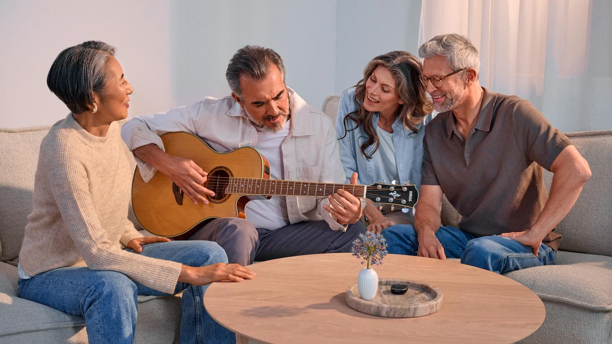 Friends enjoying a casual guitar session, appreciating their hearing improvement.