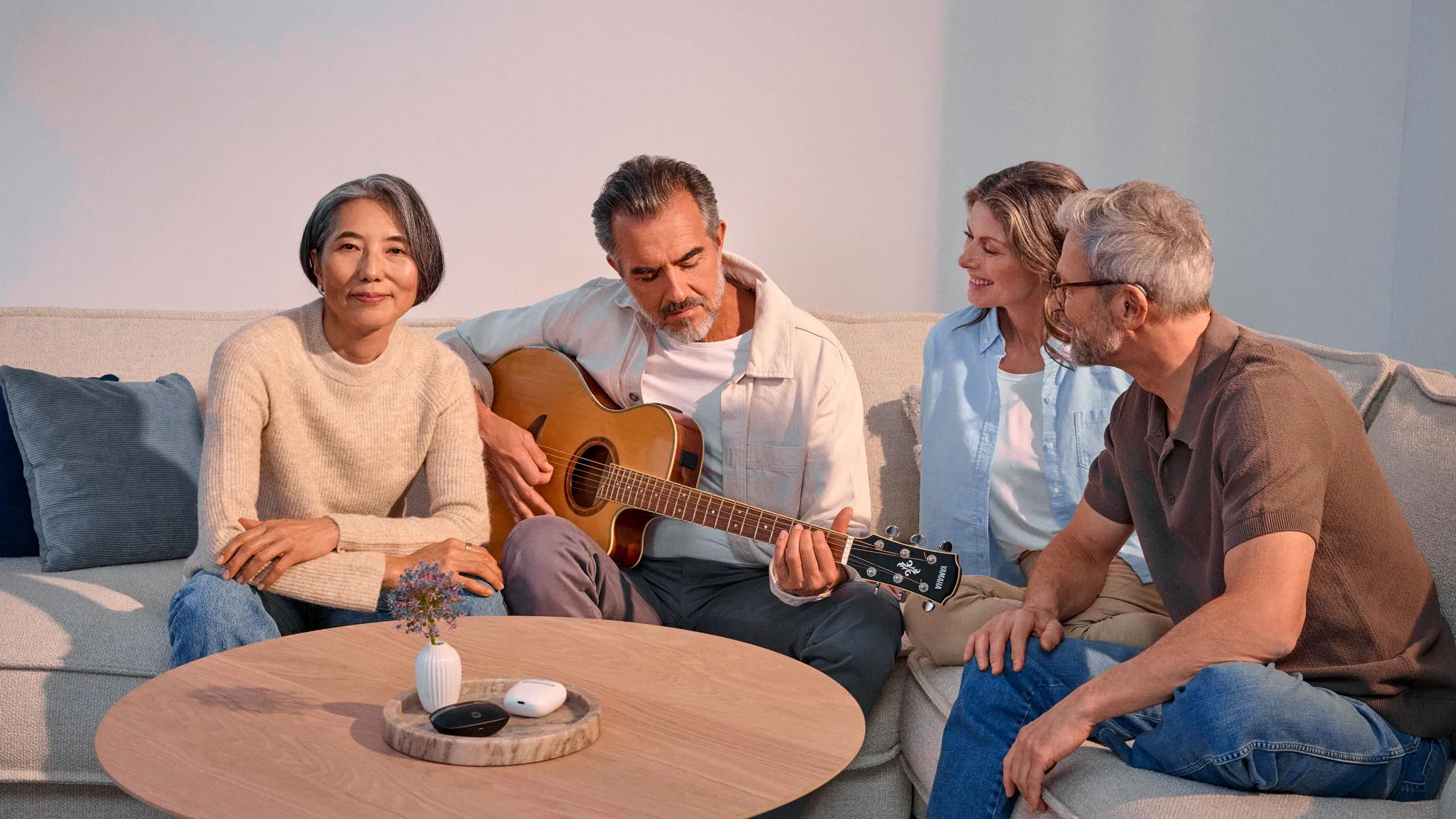 Friends interacting while playing guitar, indicating hearing improvement.