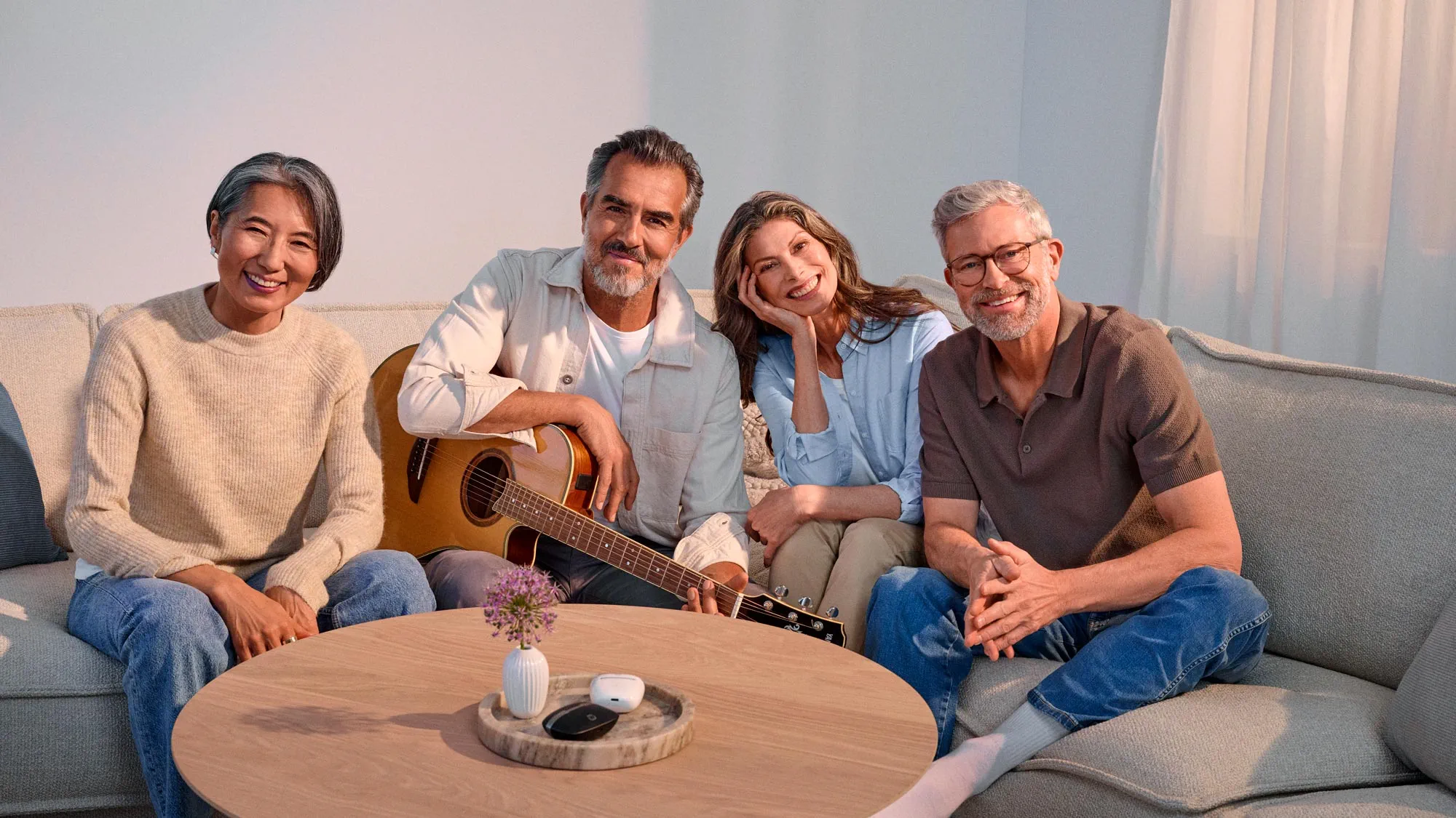 Portrait of friends with a guitar, all wearing hearing aids.