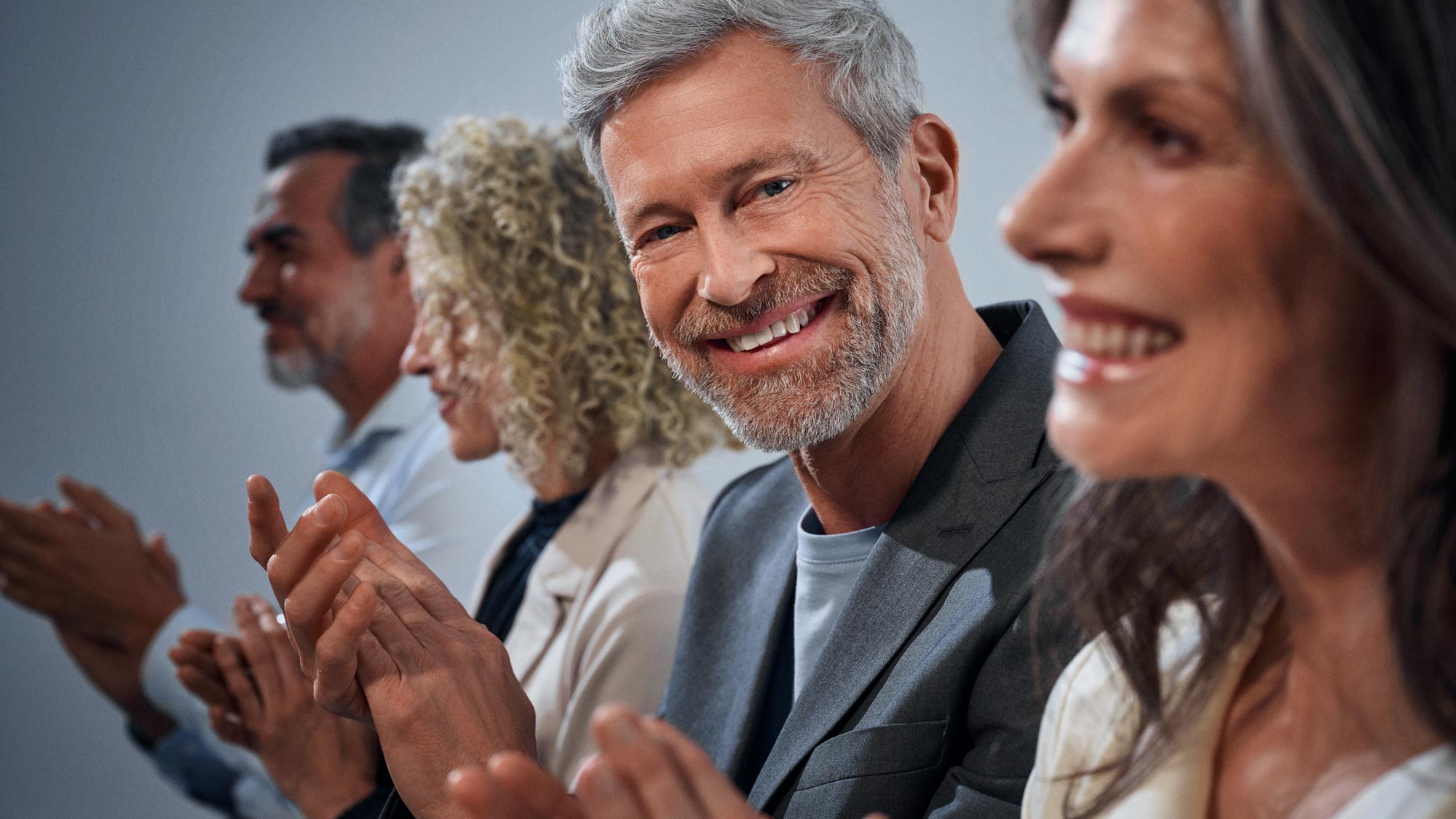 Crowd clapping and man staring hearing aids. 