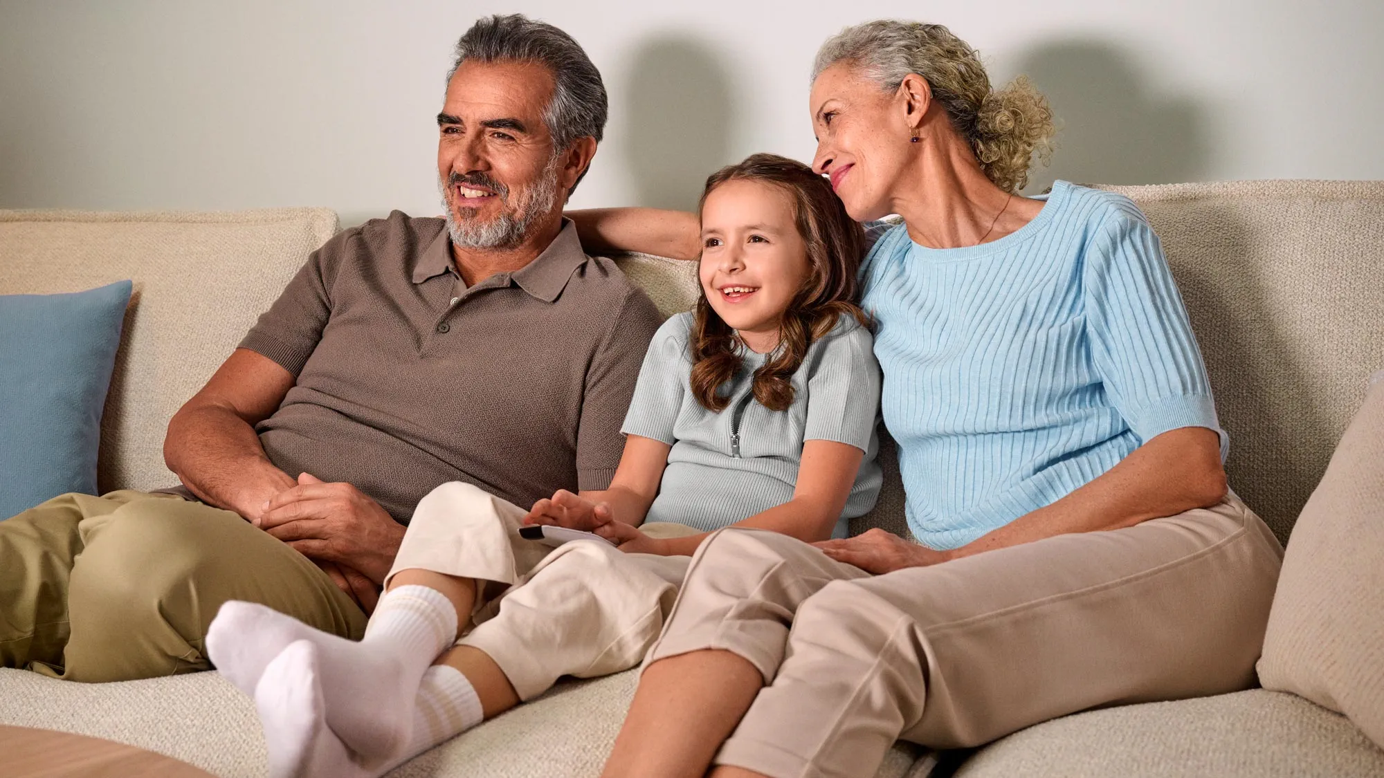 Grandparents casually watching TV, benefiting from hearing improvement.