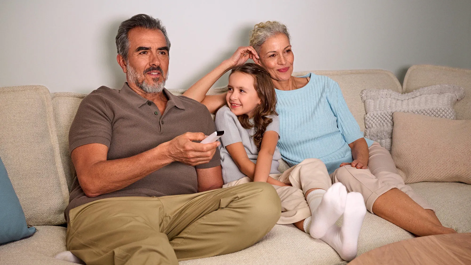 Grandparents eagerly watching TV, with hearing aids visible.