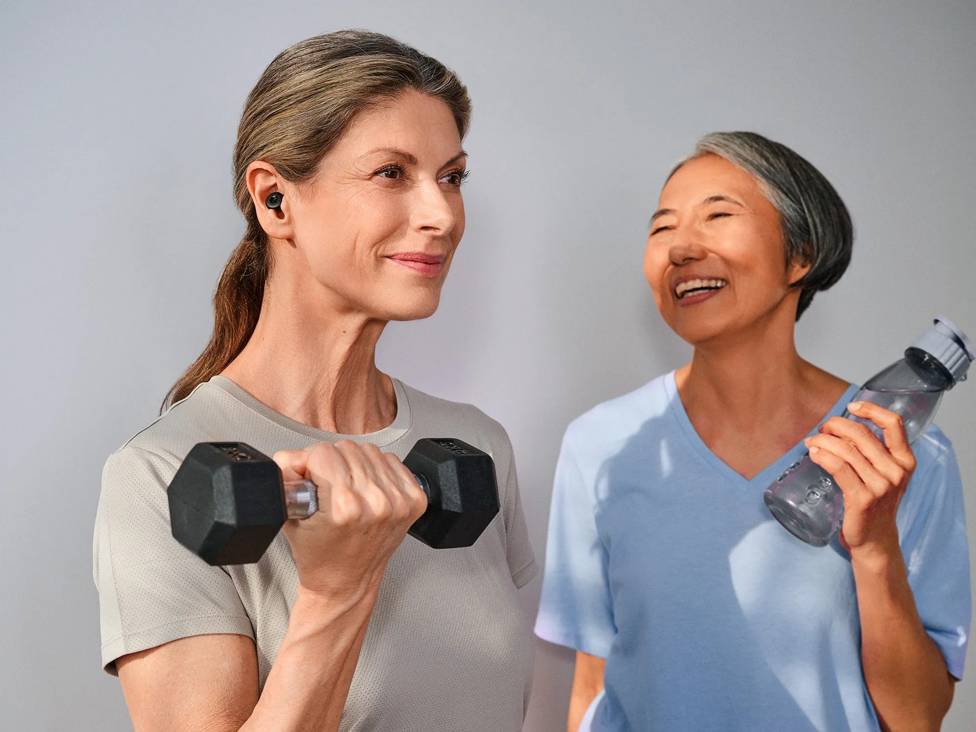 Freunde im Fitnessstudio, die sich gegenseitig inspirieren und dabei Hörgeräte tragen.