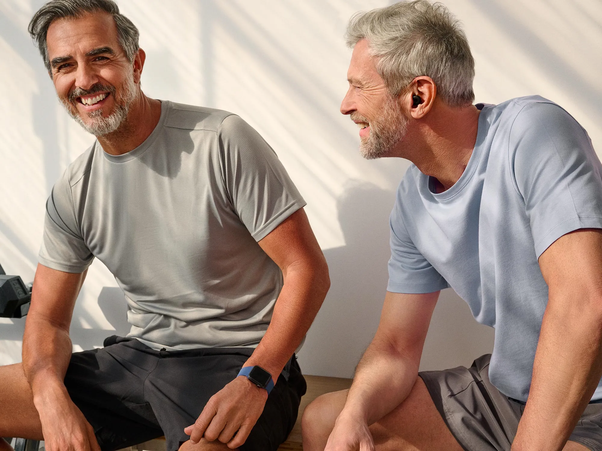 Group of men laughing at the gym, wearing hearing aids.