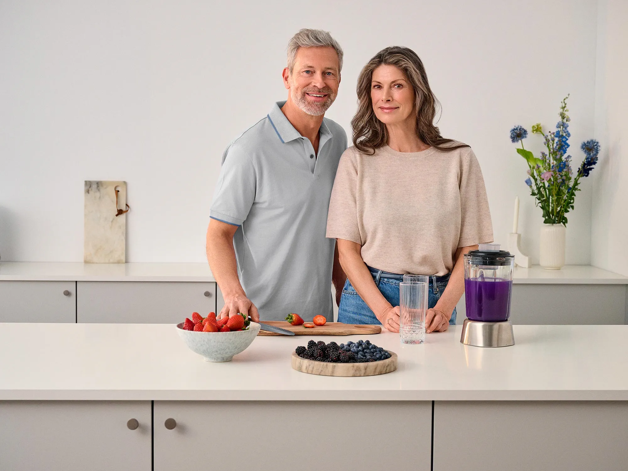 Couple cooking together in the kitchen, both wearing hearing aids.