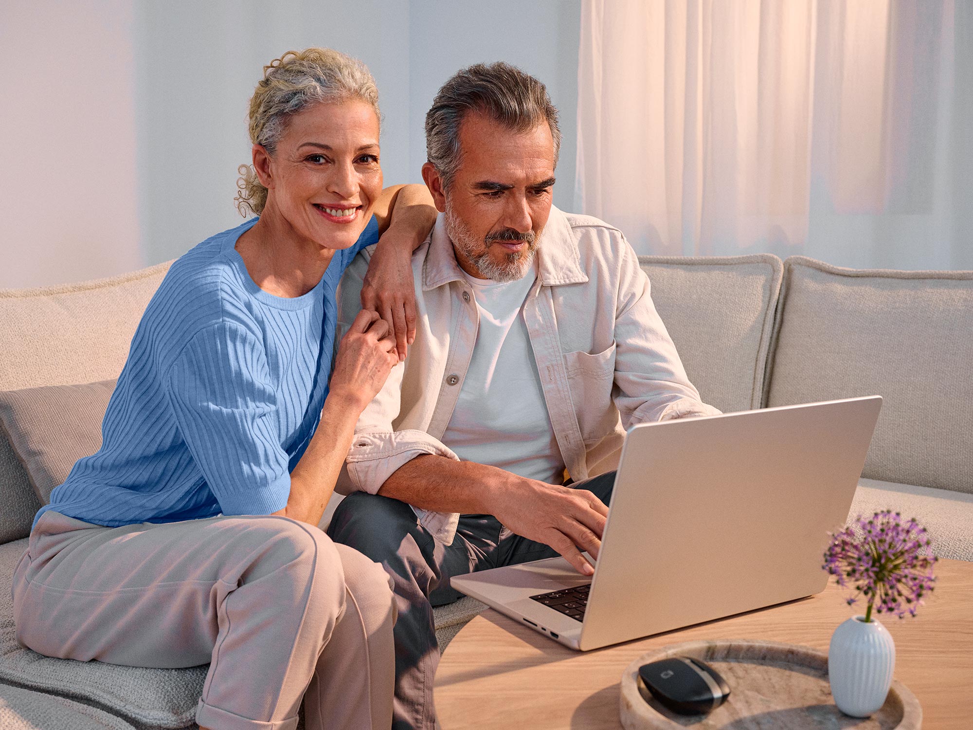 Hopeful couple with technology, both wearing hearing aids.