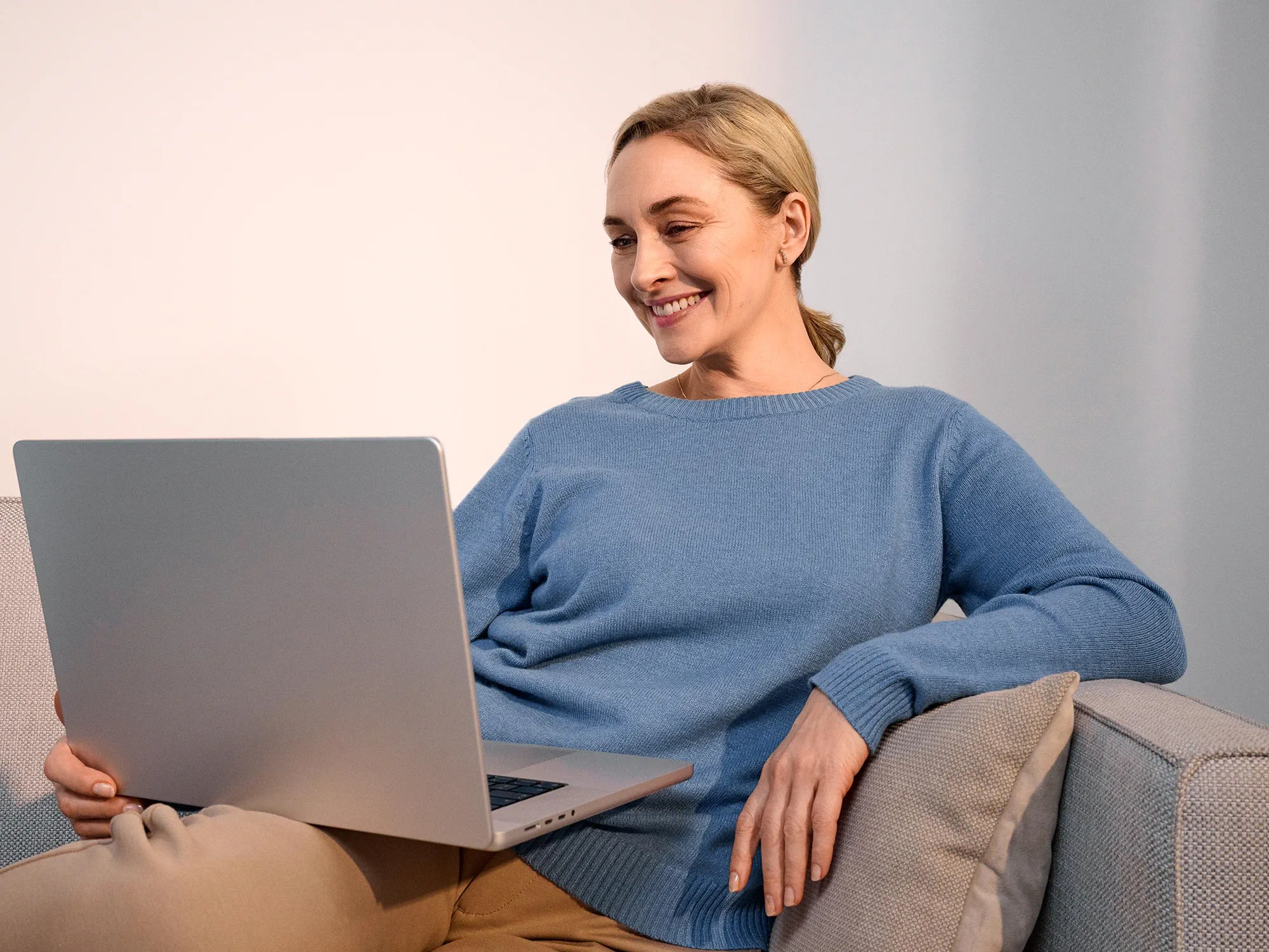 Smiling woman working on a computer, with hearing aids visible.