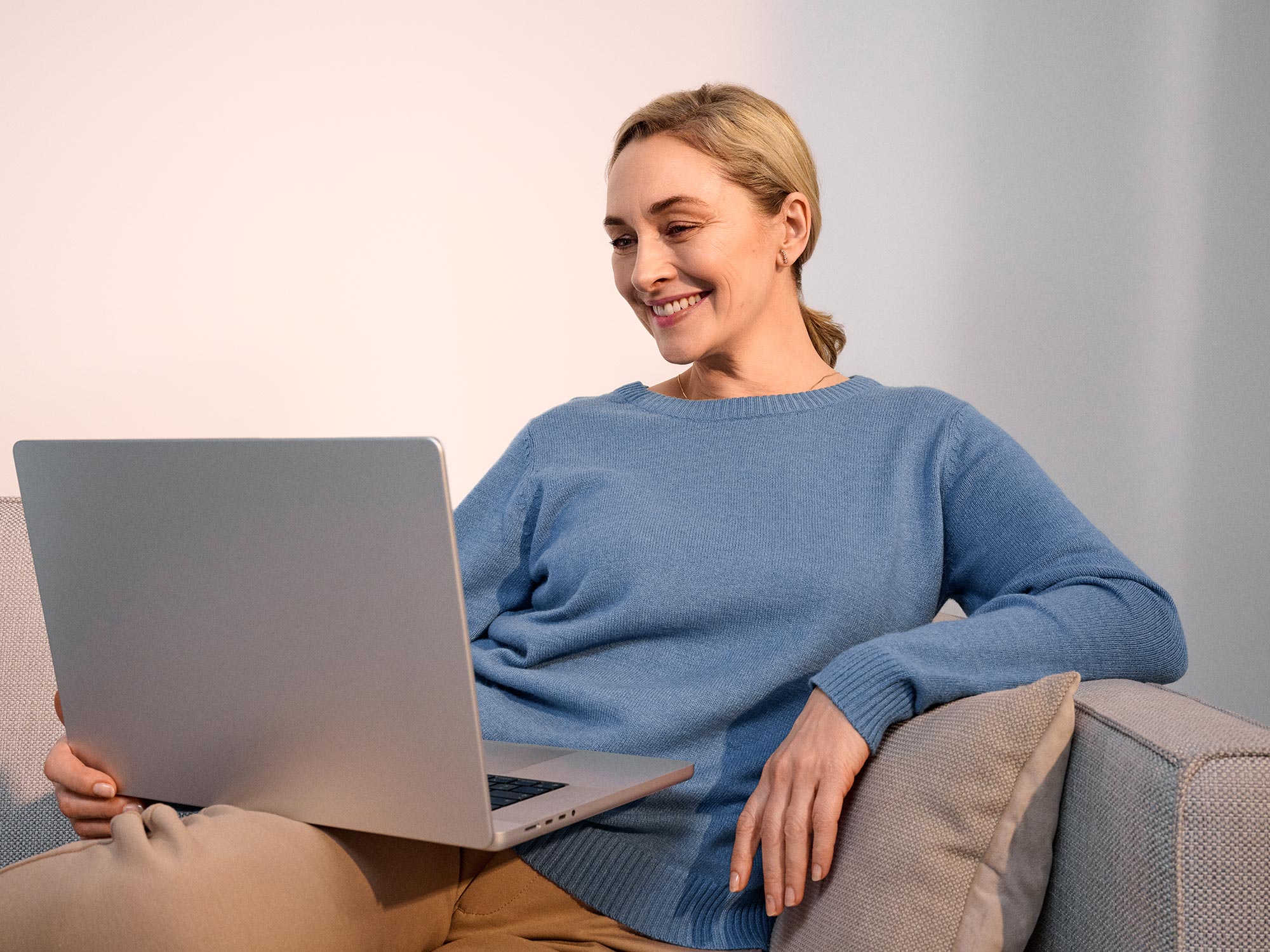 Smiling woman working on a computer, with hearing aids visible.