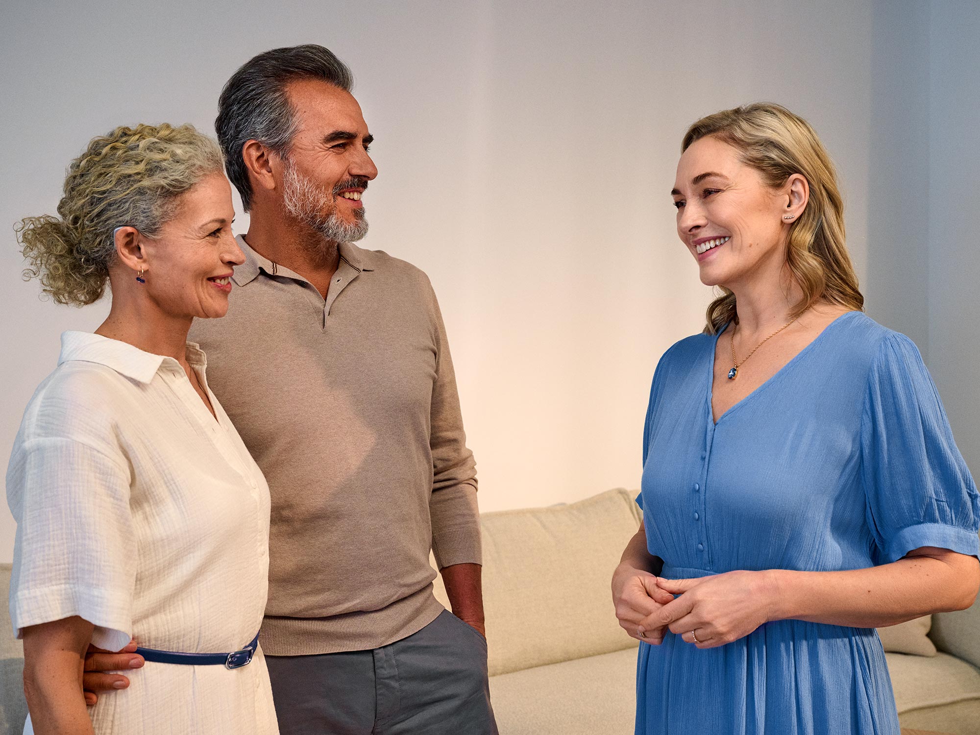 Couple talking with a friend, enjoying conversation thanks to hearing improvement.