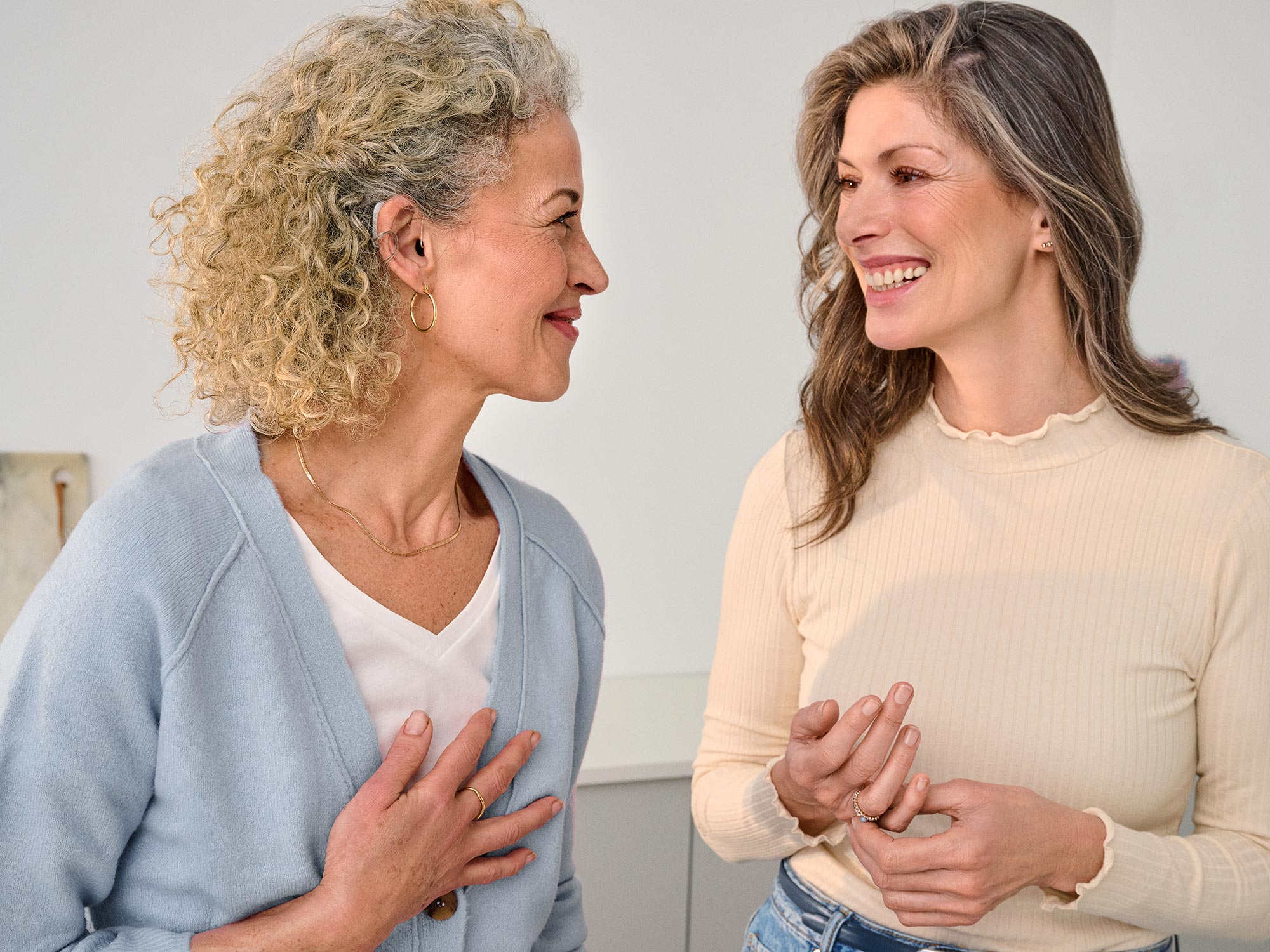 Close group of friends chatting together, all with hearing aids.