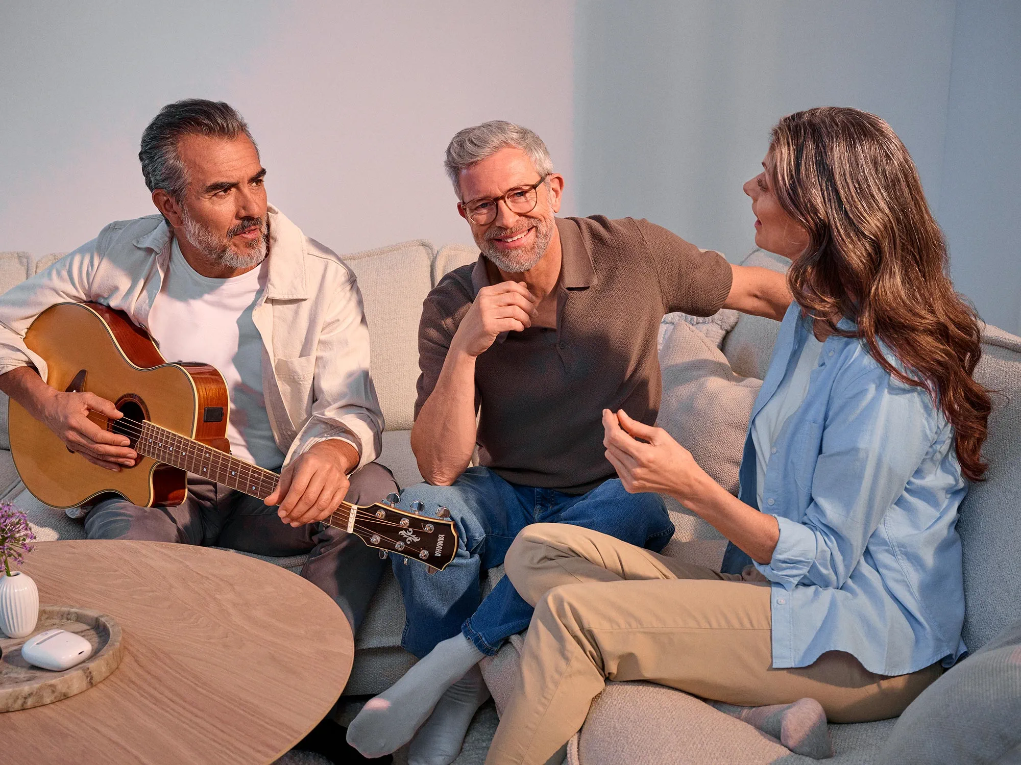 Freunde unterhalten sich beim Gitarrespielen und tragen Hörgeräte.