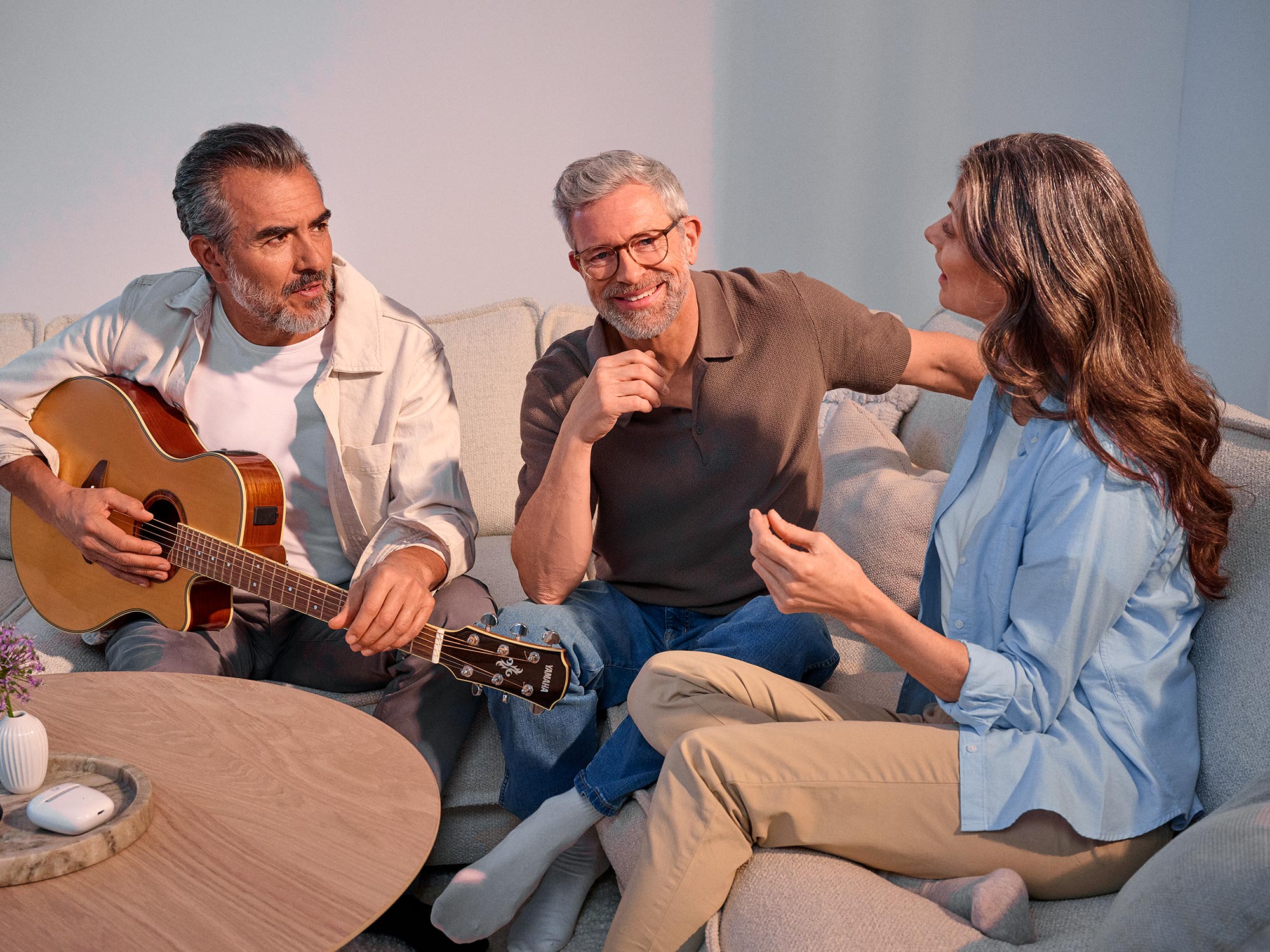 Freunde unterhalten sich beim Gitarrespielen und tragen Hörgeräte.