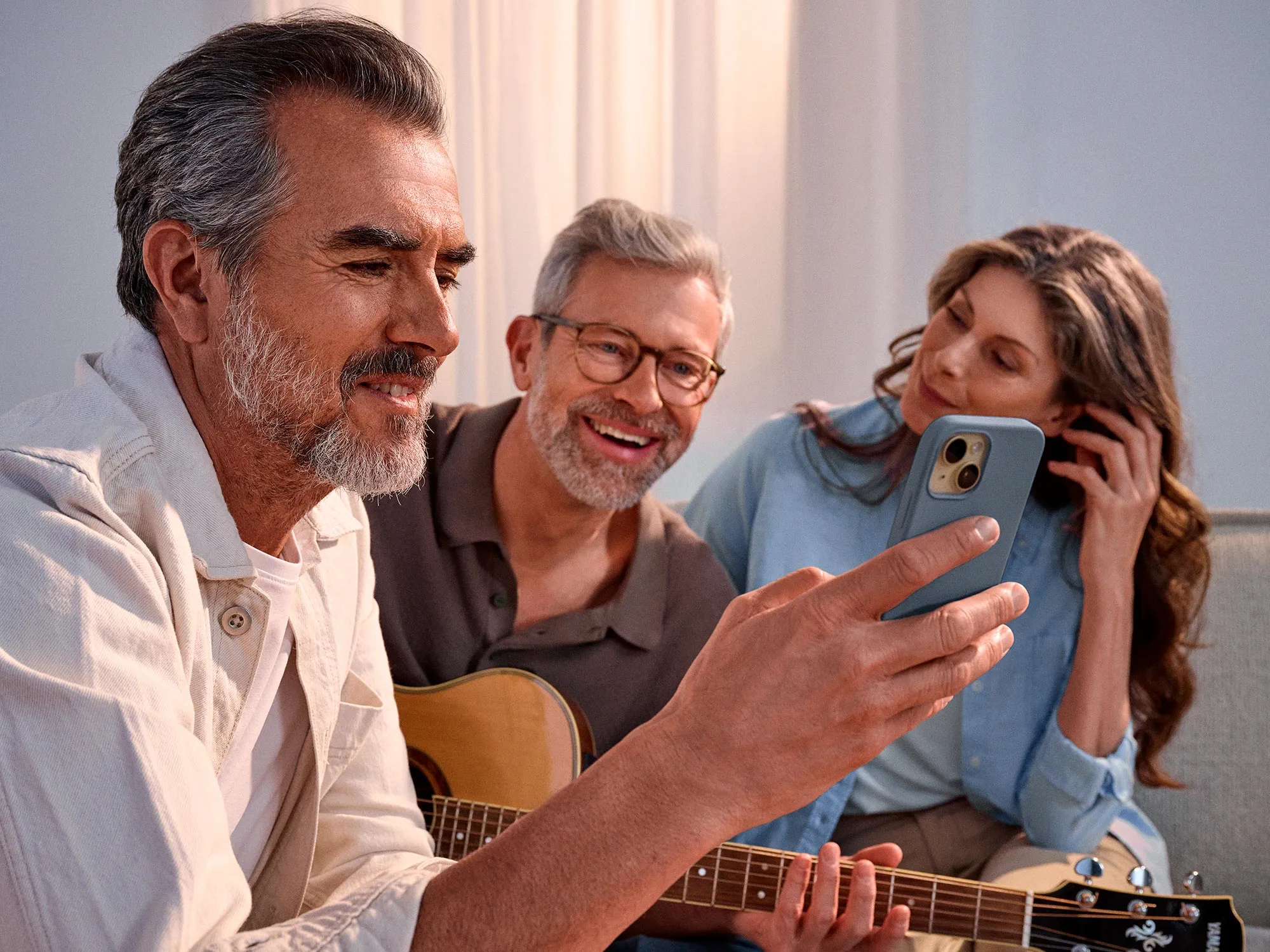 Casual group of friends looking at a phone, celebrating their hearing improvement.