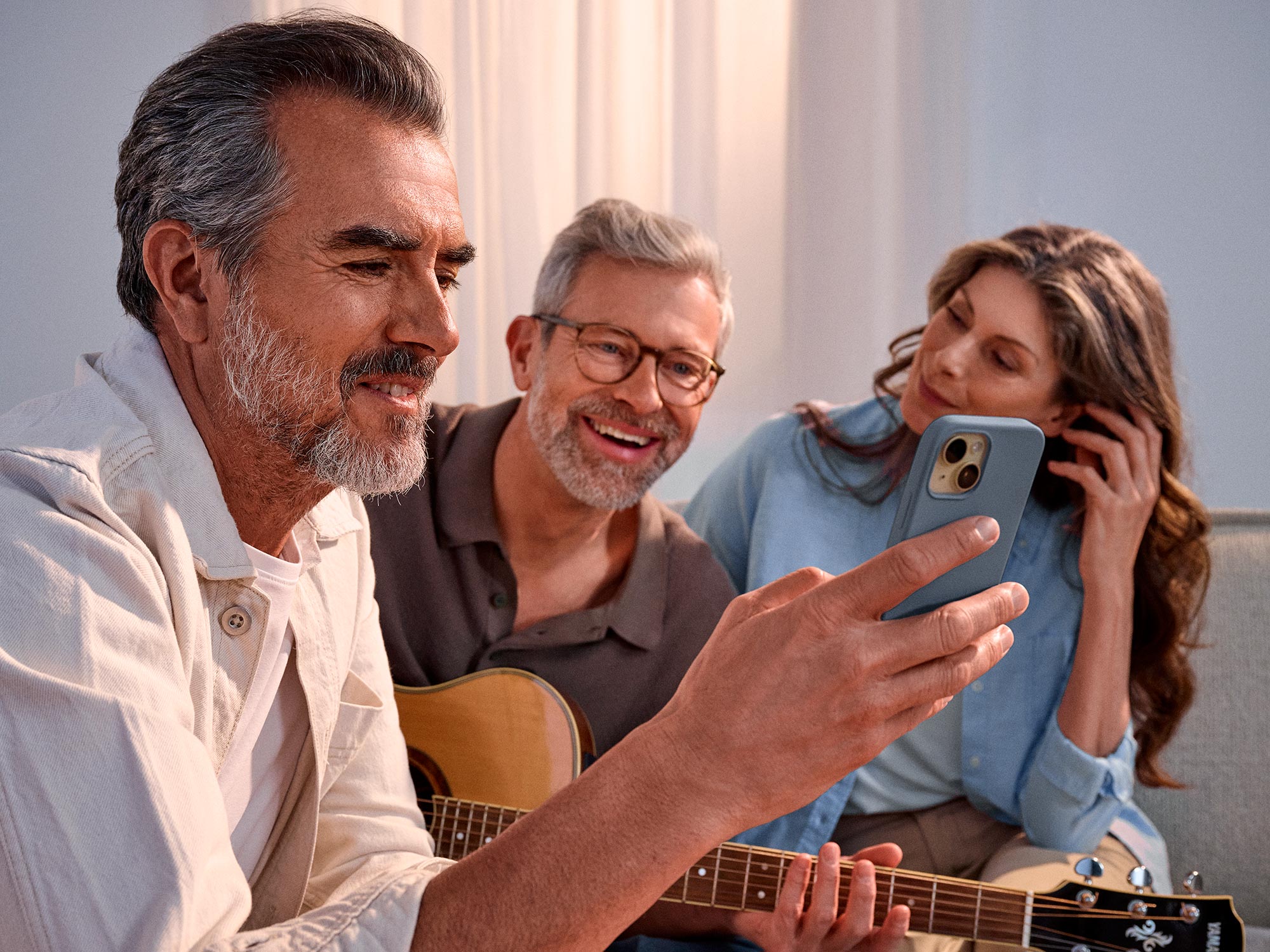 Casual group of friends looking at a phone, celebrating their hearing improvement.