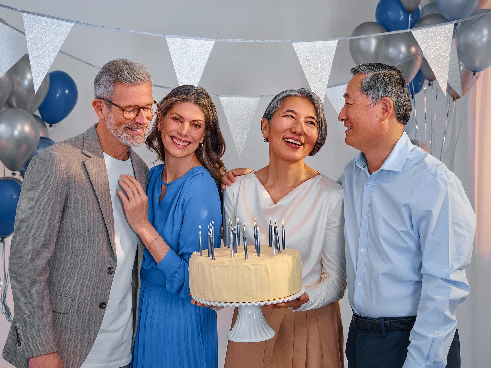Freunde, die sich bei einem Geburtstag einander ansehen und dadurch auf eine Verbesserung des Hörvermögens hinweisen.