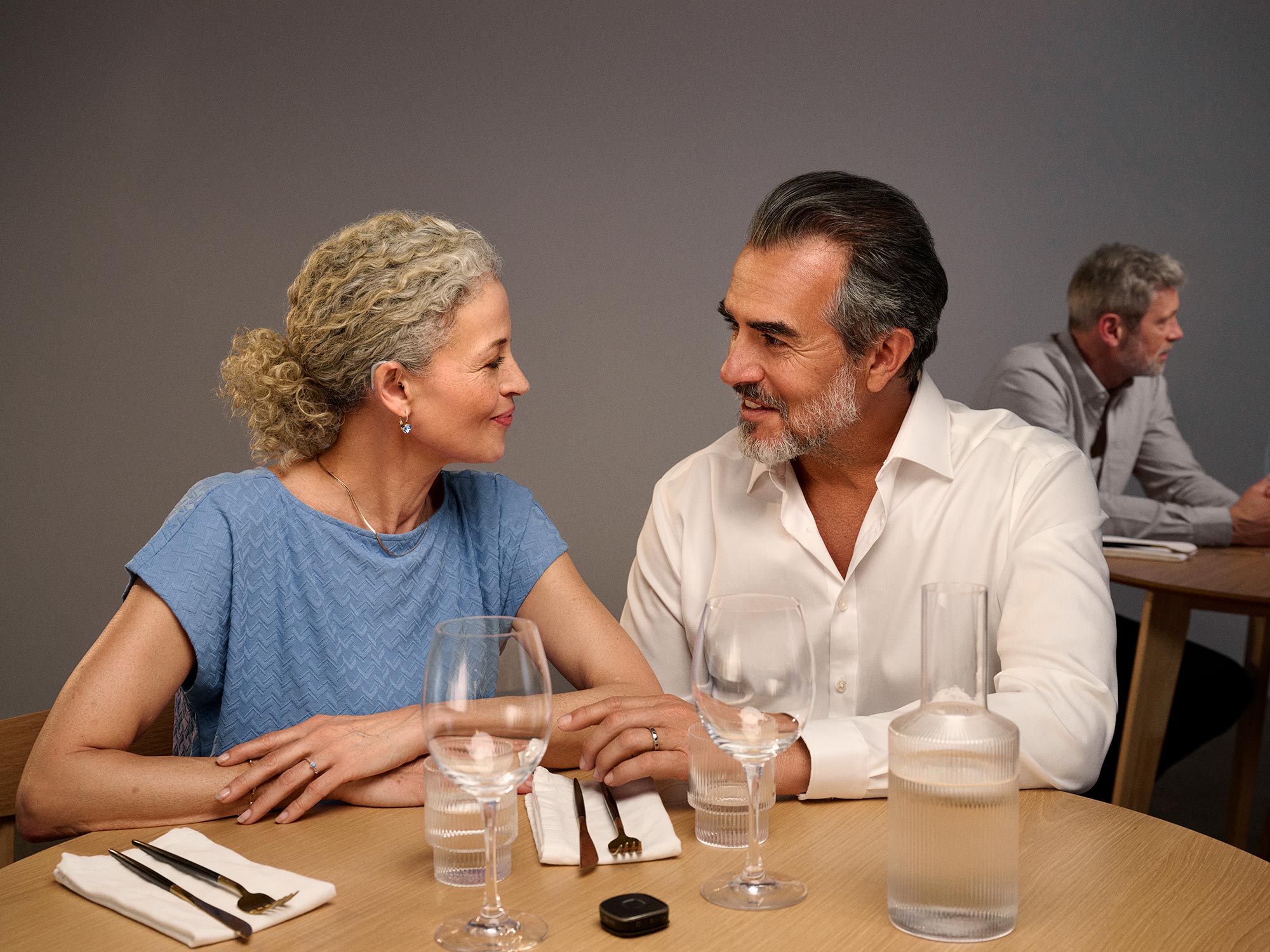 Casual dinner setting with a couple, both wearing hearing aids.