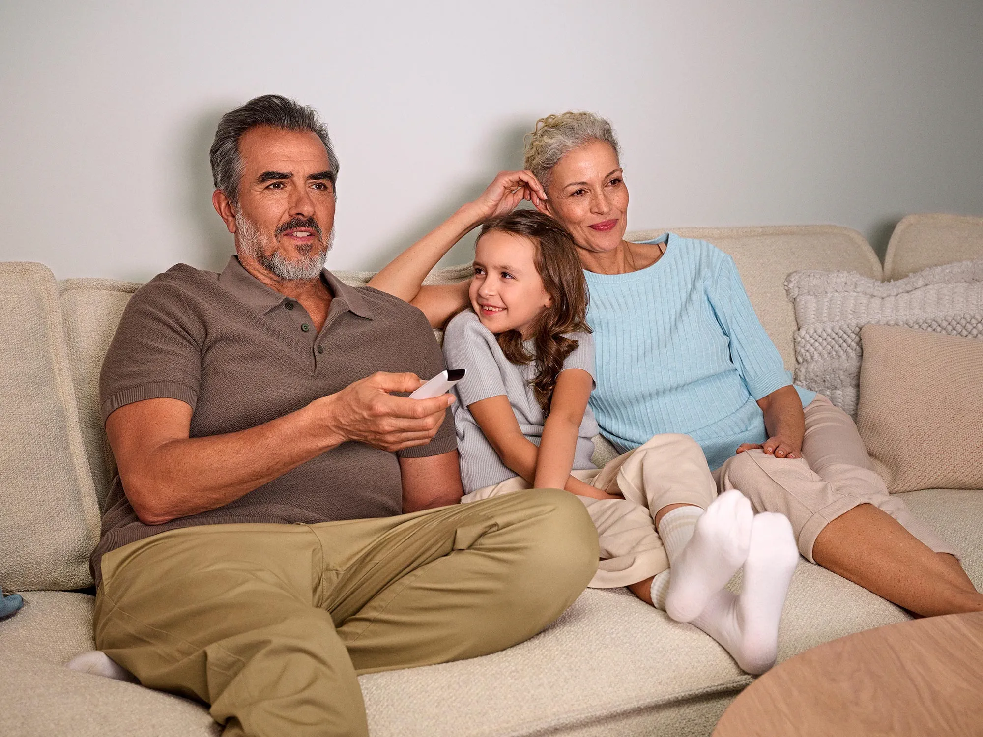 Grandparents eagerly watching TV, with hearing aids visible.