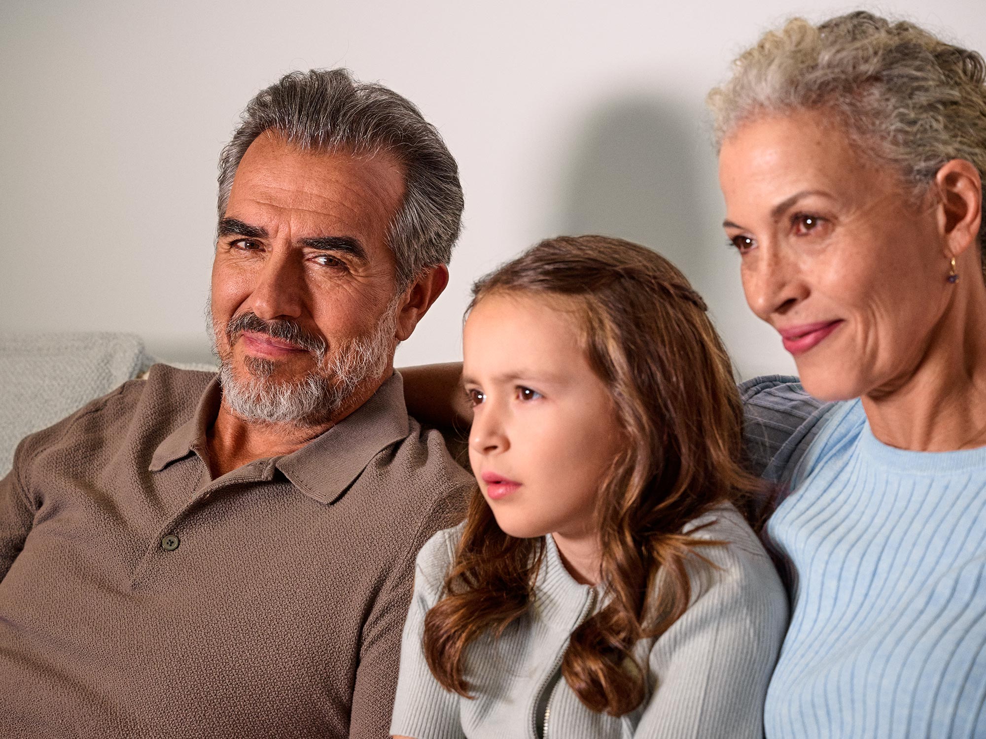 Grandparents and girl watching, showcasing hearing aids.