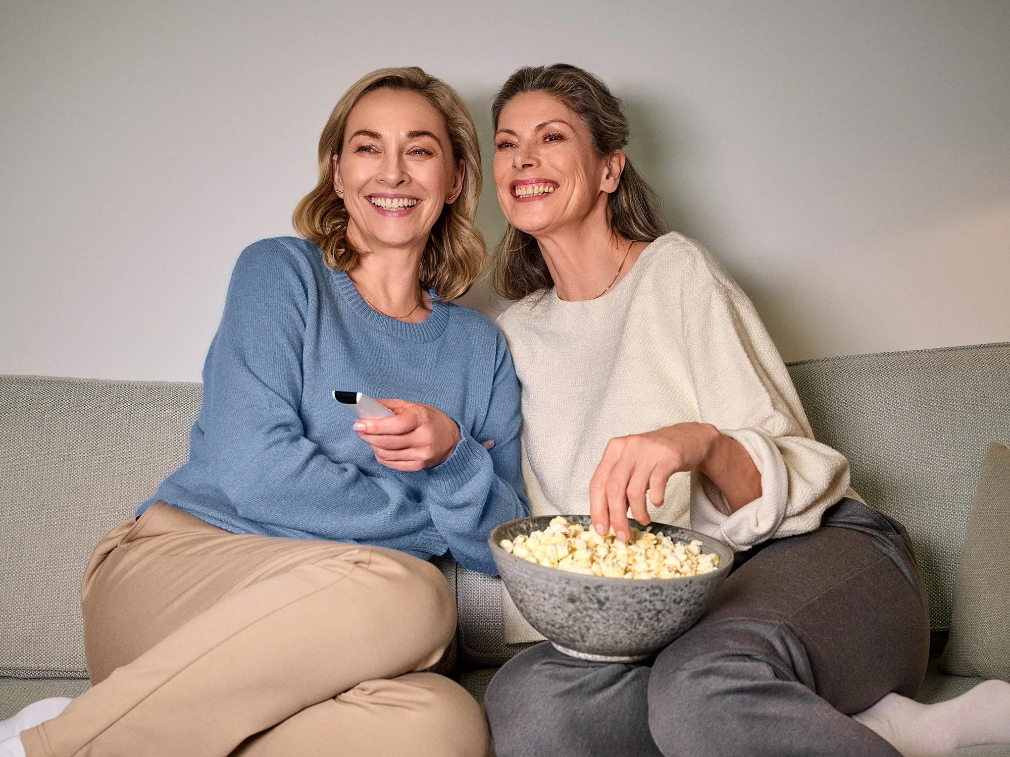 Women laughing together while watching TV, all wearing hearing aids.