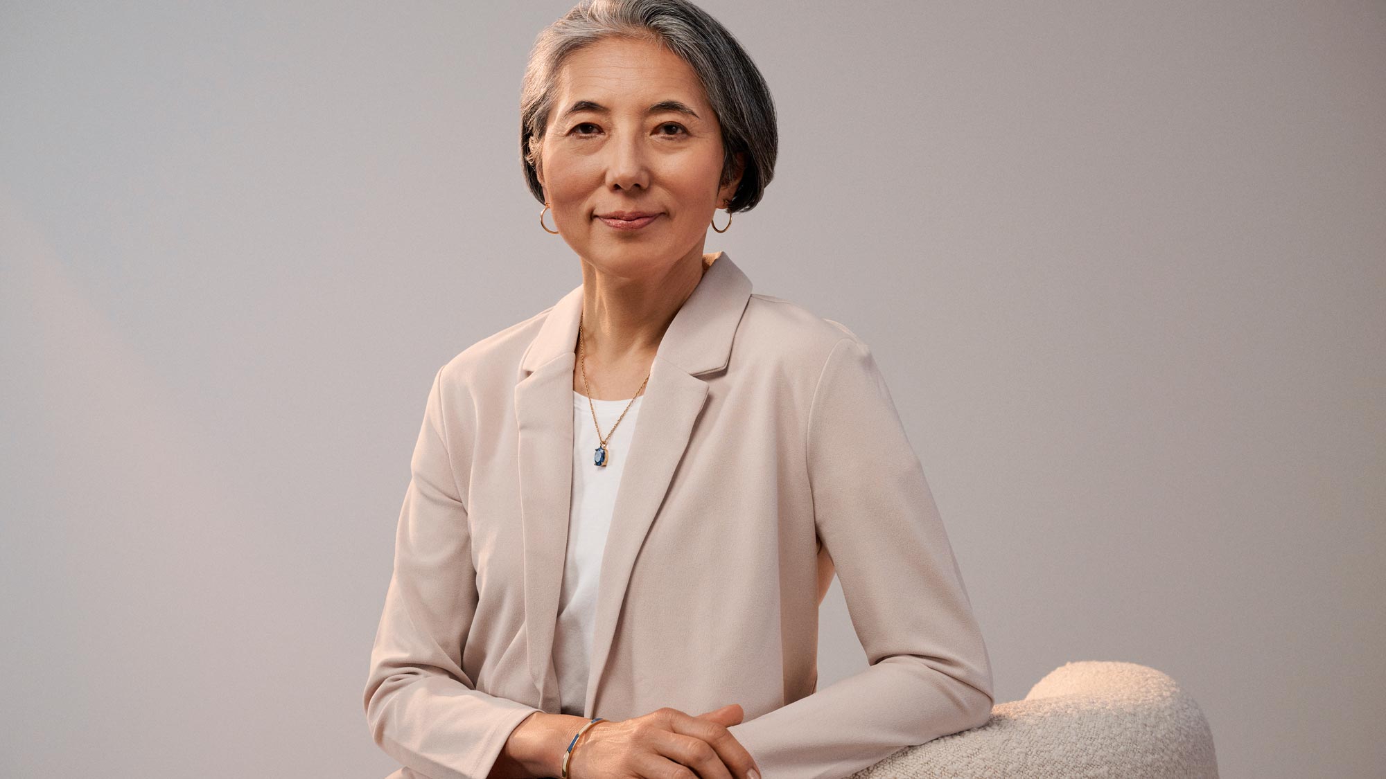 Confident woman sitting, wearing hearing aids.