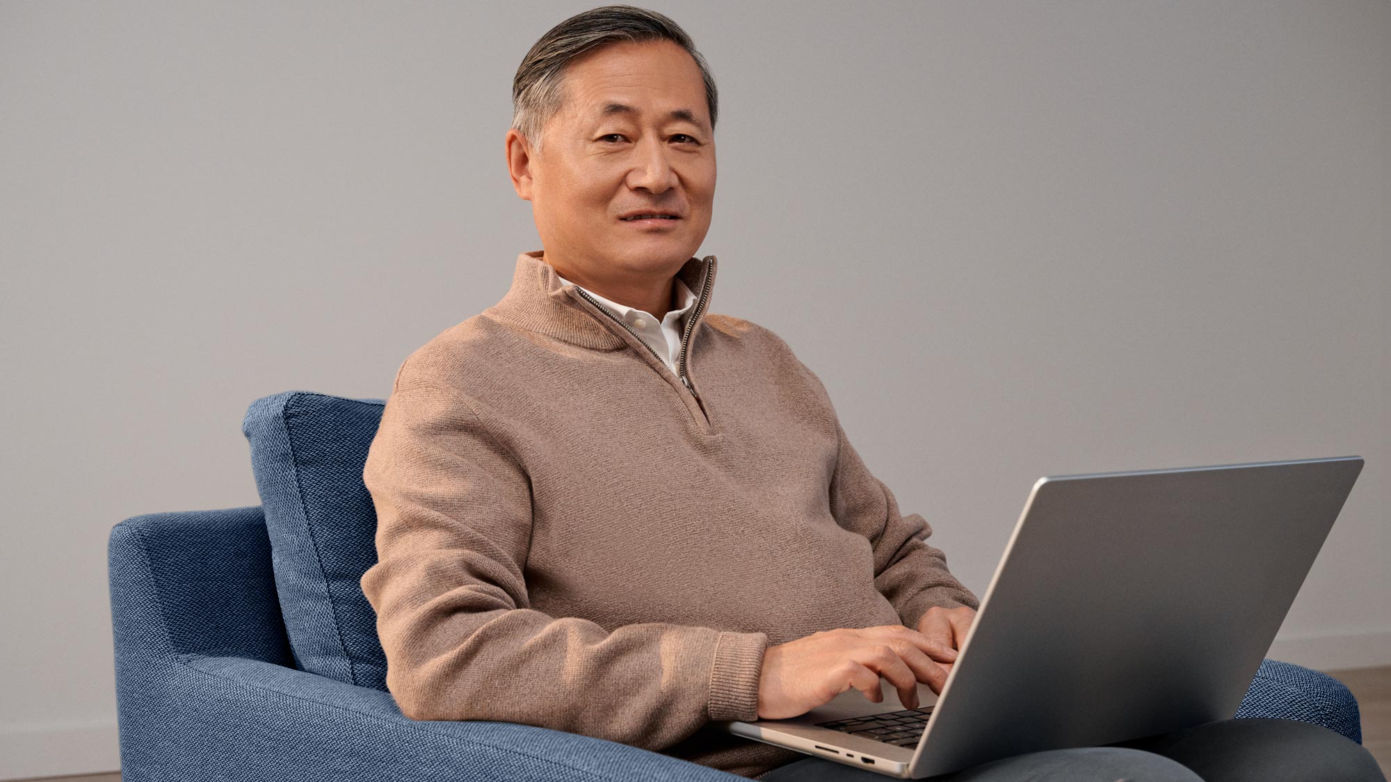 Content man working on a computer, wearing hearing aids.