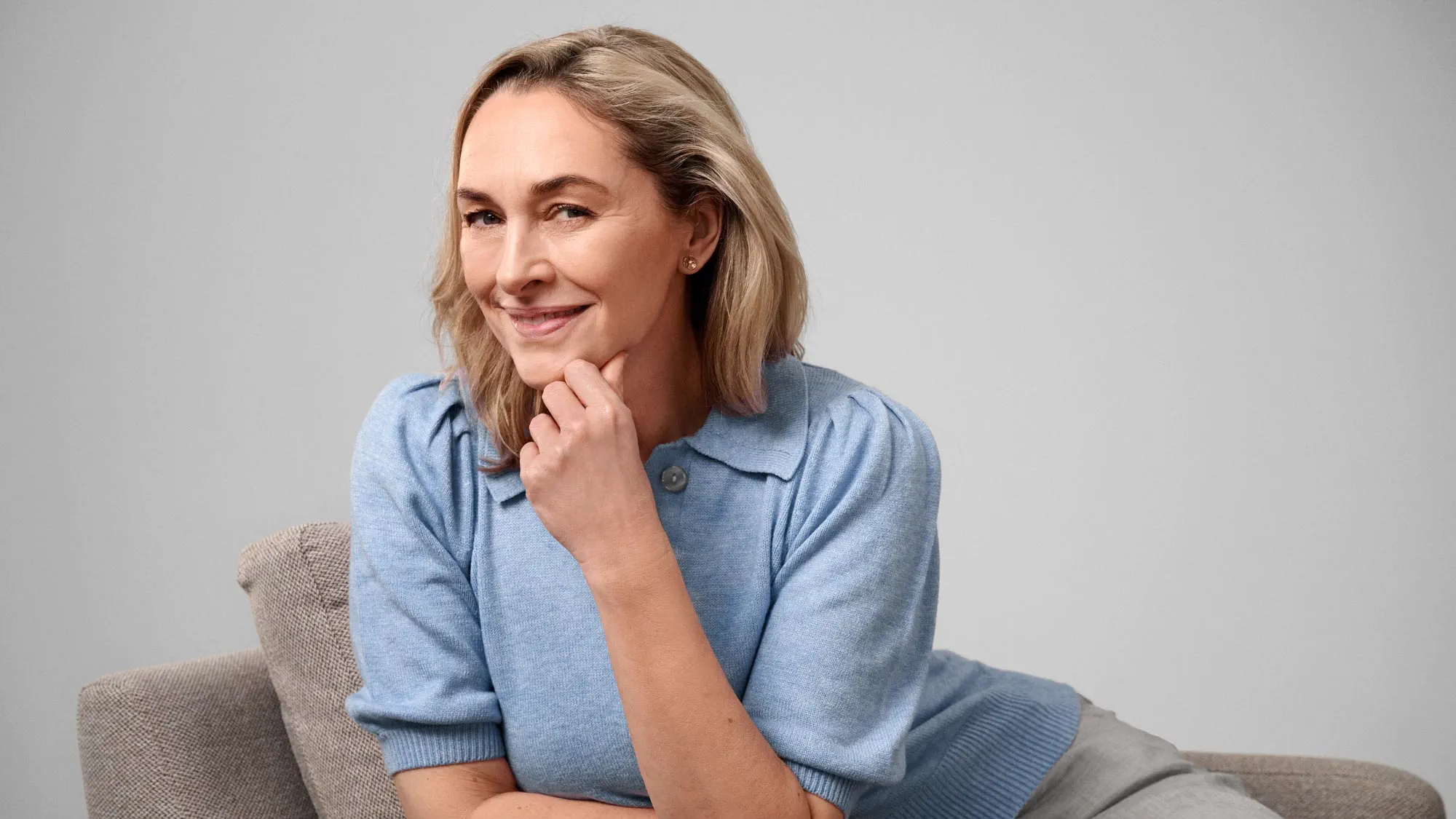 Content woman sitting comfortably, wearing hearing aids.