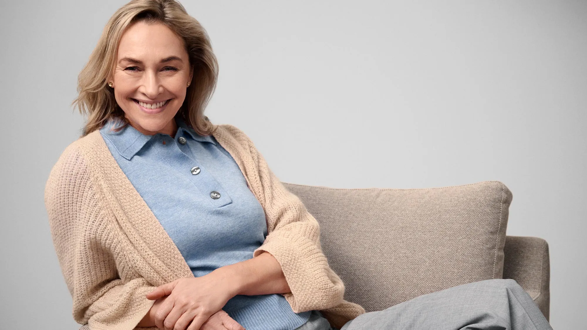 Happy woman sitting, indicating hearing improvement.