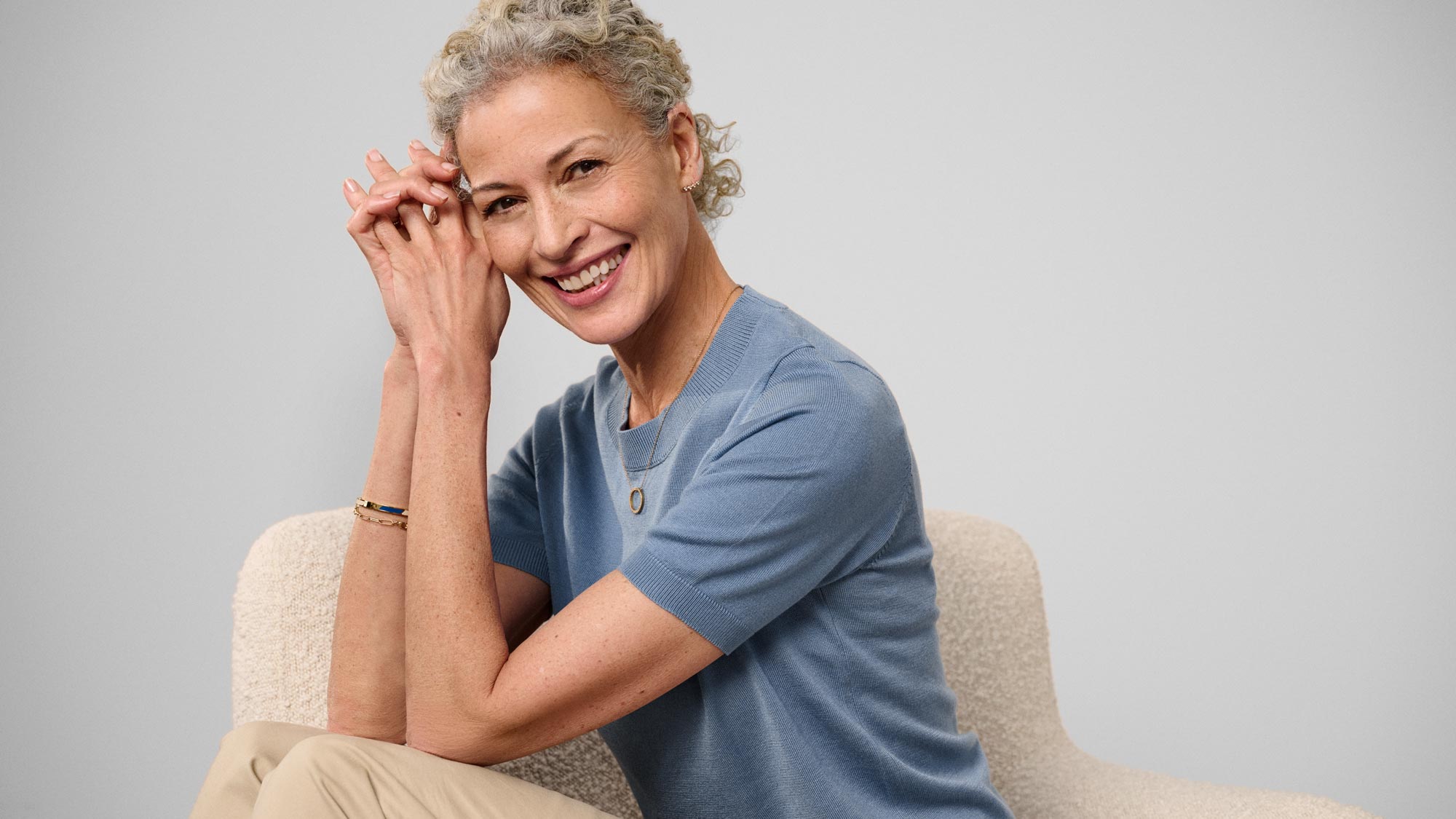 Happy woman sitting, showcasing hearing aids.