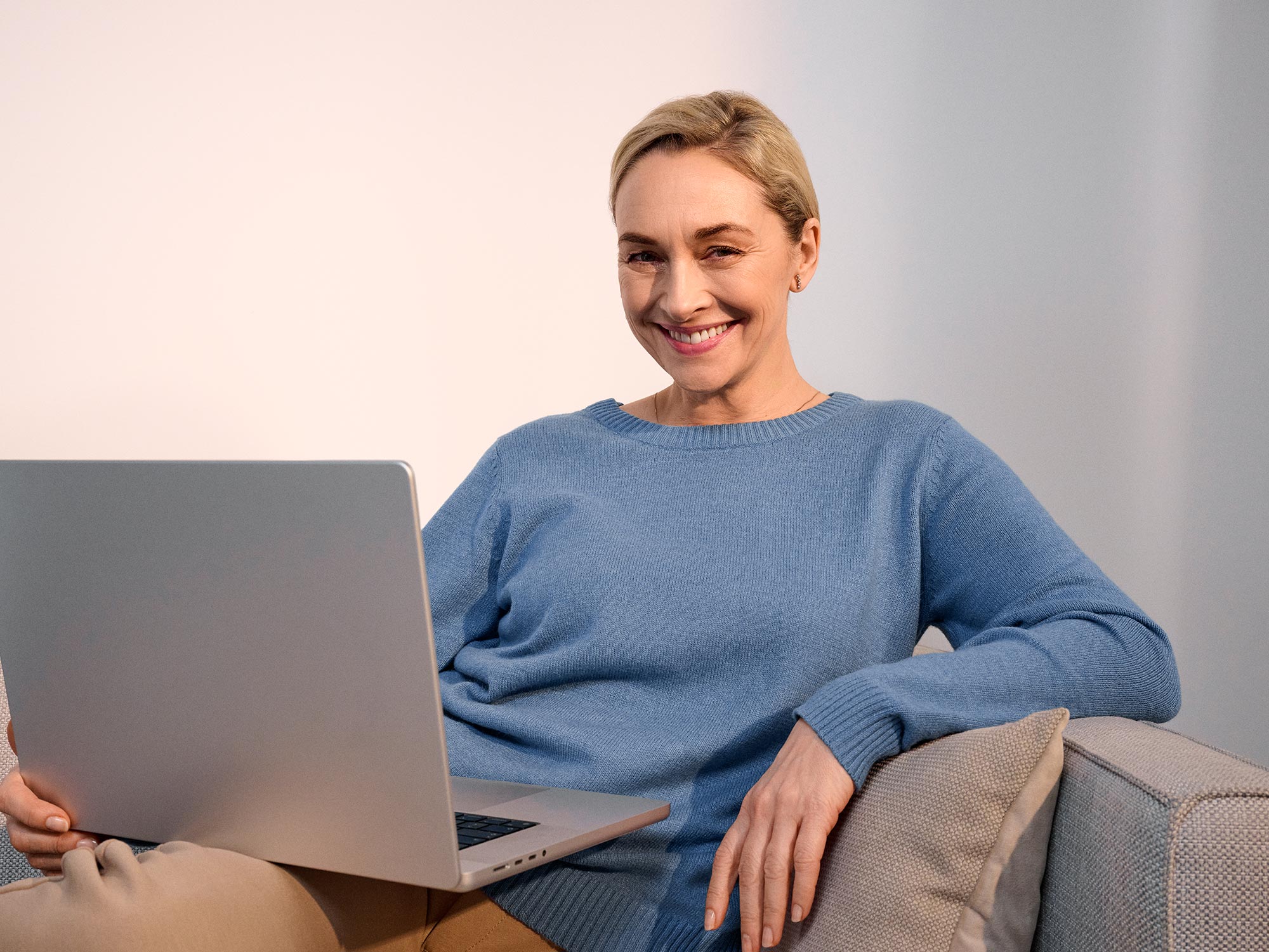 Glückliche Frau benutzt einen Computer und trägt Hörgeräte.