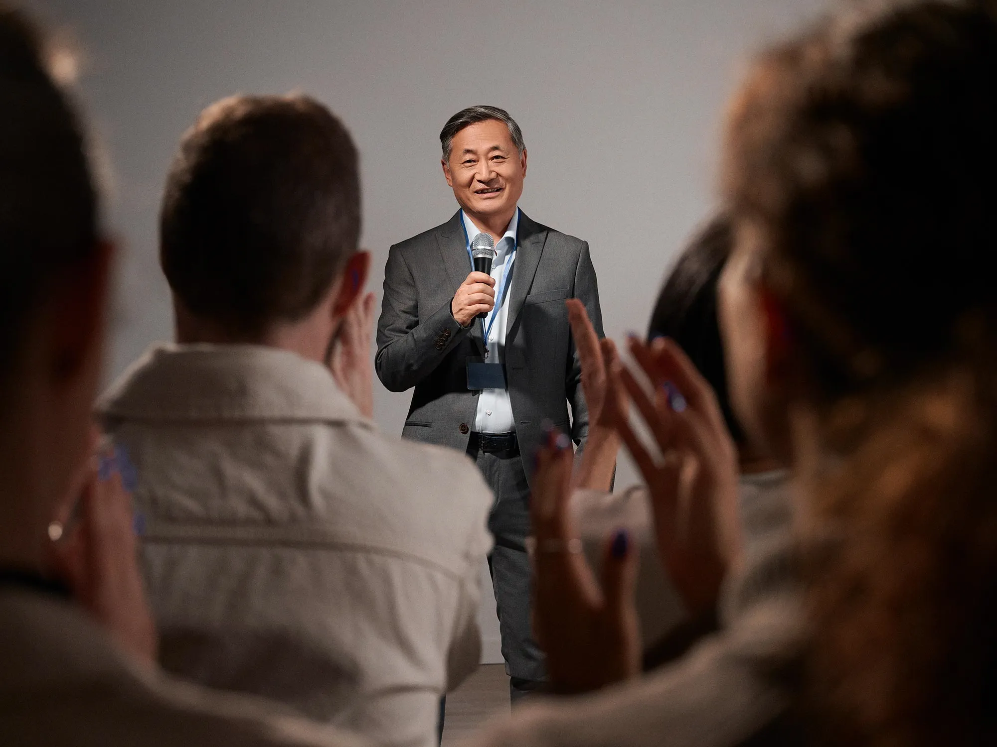 Man presenting to an audience, discussing hearing improvement.