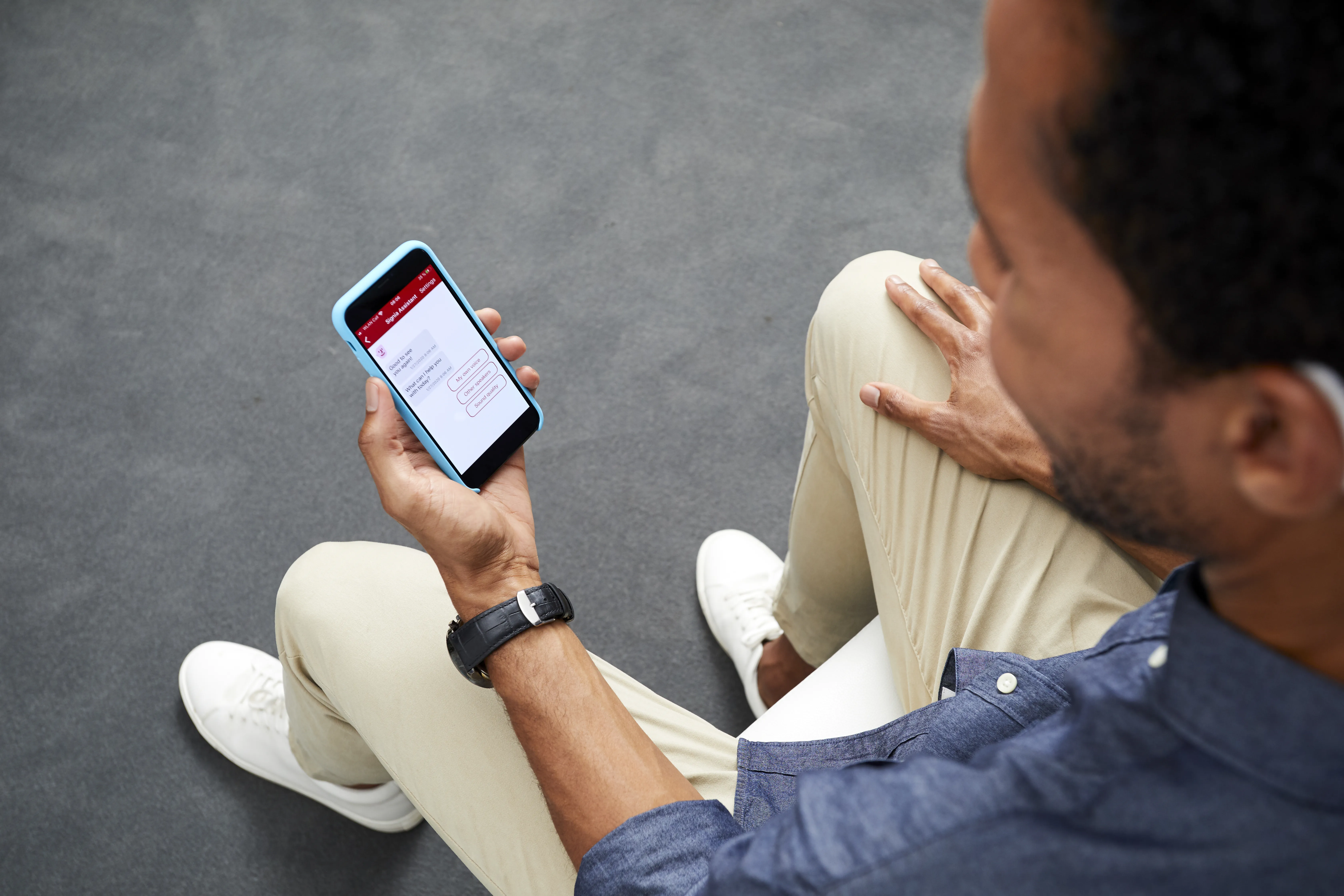  Man looking at phone with Signia Assistant app helping you control your hearing aids